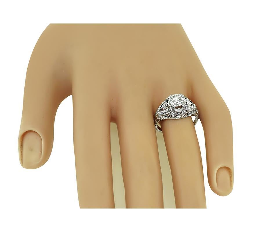 This is an amazing platinum engagement ring from the Art Deco era. The ring is center with sparkling GIA certified round cut diamond that weighs 1.12ct. The color of the diamond is E with SI2 clarity. The center diamond is accentuated by dazzling