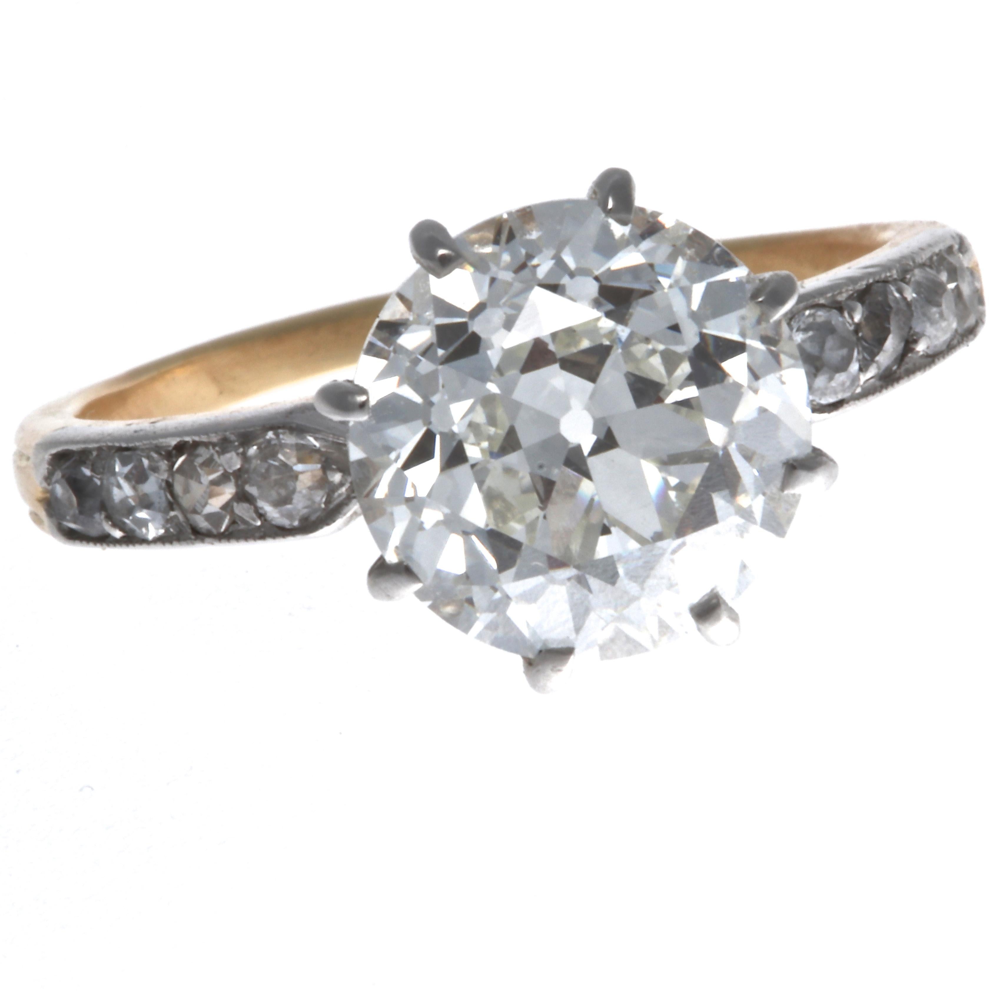 This stunning Art Deco diamond engagement ring features a GIA certified 3.23  carat, J color, VVS2 clarity round cut diamond. Held in place by 8 prongs, this shimmering center stone is adorned with 7 old European cut and 1 single cut diamond, that