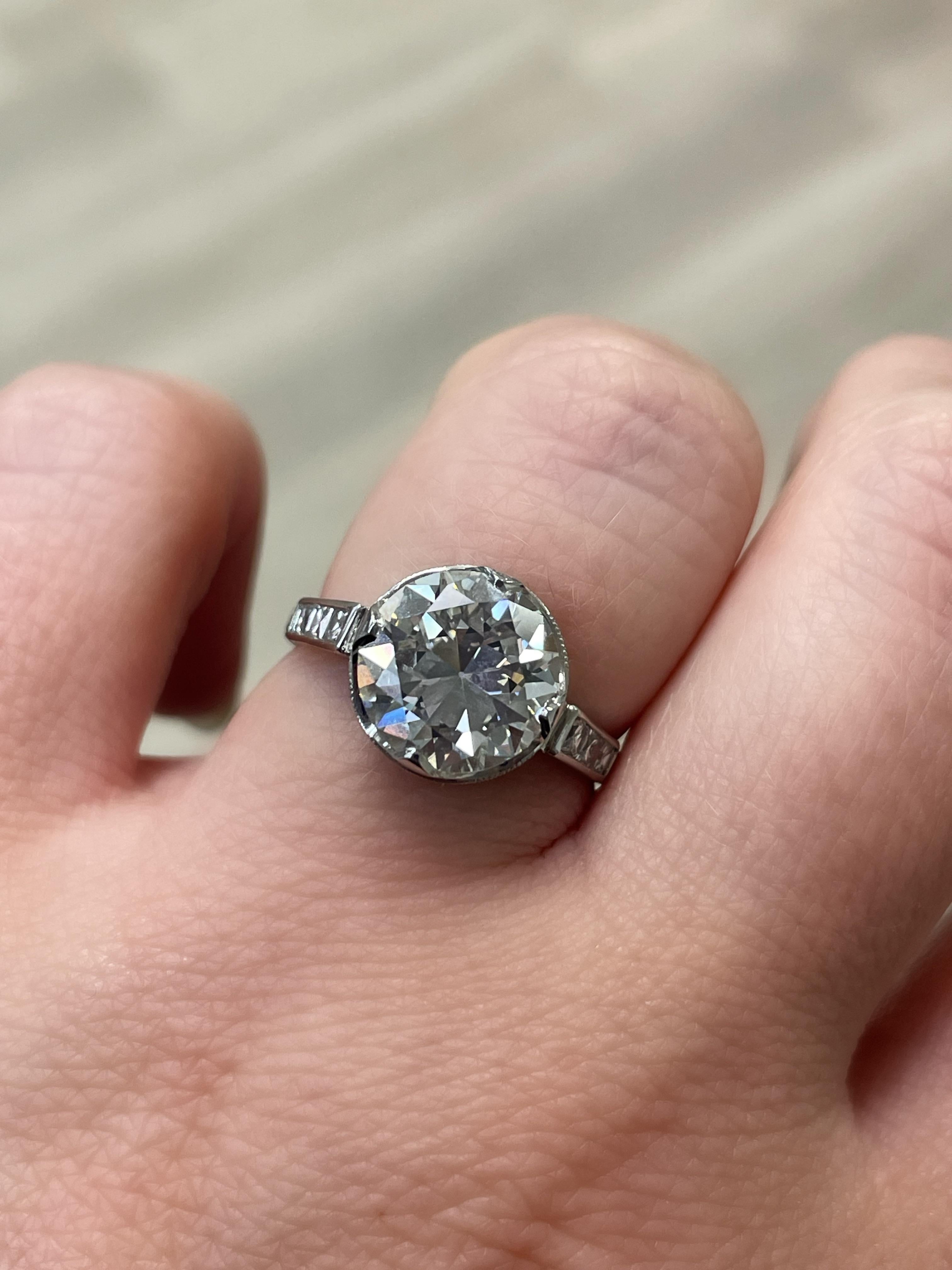 This beautiful and authentic Art Deco diamond engagement ring boasts an Old European cut diamond weighing 3.31 carats flanked by 6 French cut diamonds on the shoulders and single cut diamonds on the gallery. Mounted in platinum, with a swirling open