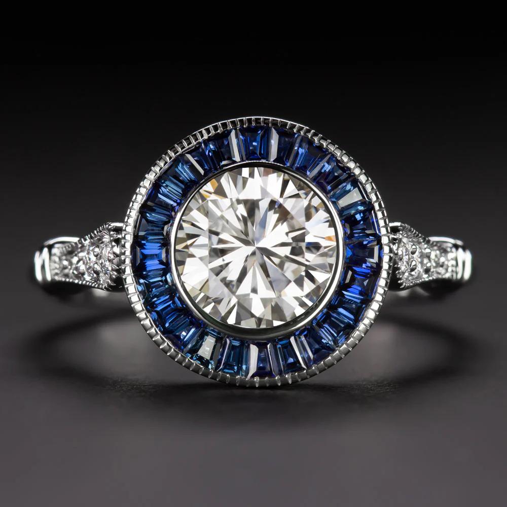 Cette bague raffinée d'inspiration Art of Vintage allie des proportions élégantes à une géométrie vintage, mettant en valeur un diamant rond de taille brillant de 0,96 carat certifié par la GIA en son centre. Classé de couleur K avec une face