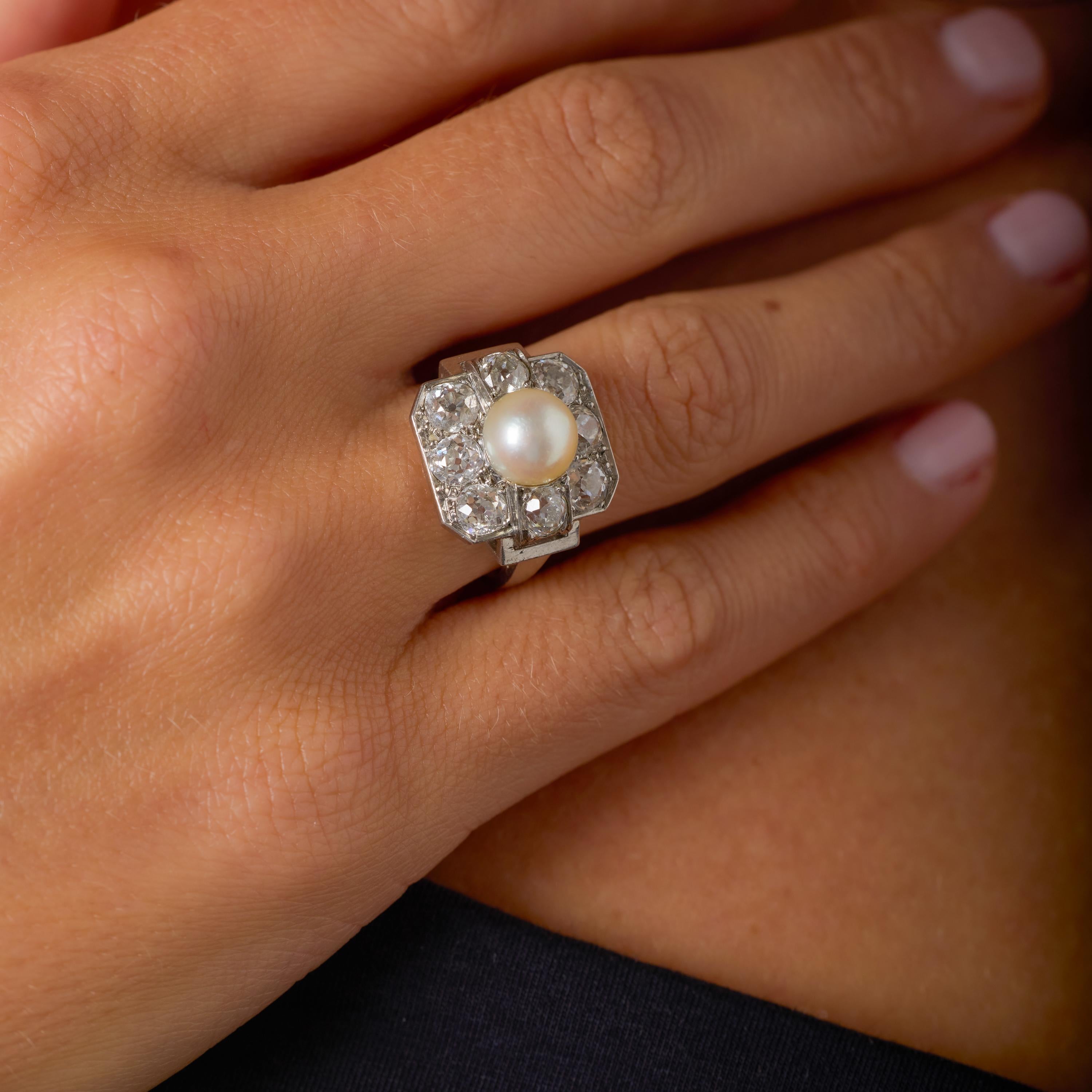 Este exquisito anillo Art Déco reúne dos de los elementos más románticos de la joyería antigua: una luminosa perla natural y el brillo intemporal de los diamantes de talla europea antigua. En su centro descansa una perla natural certificada de
