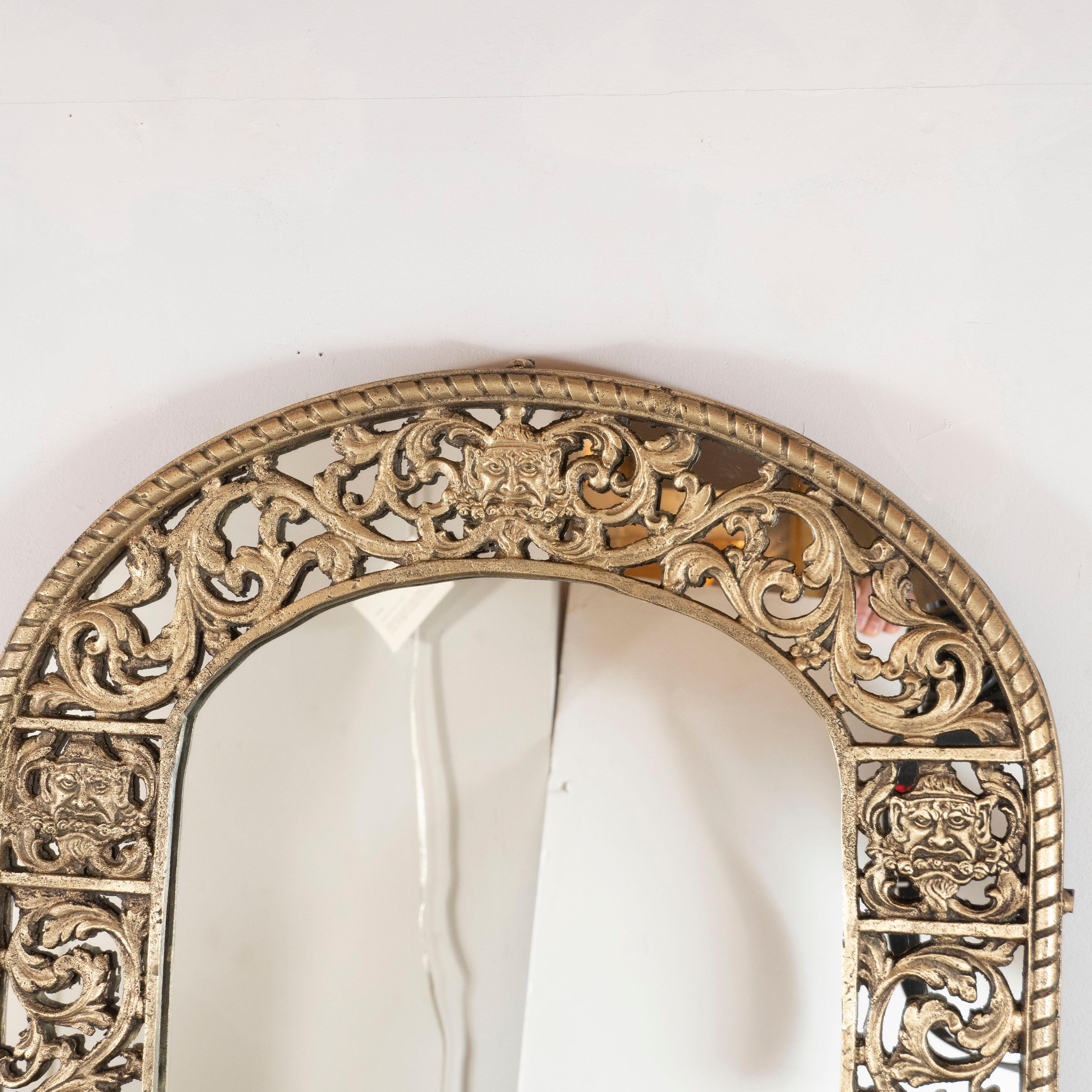 This sophisticated mirror was realized in the United States, circa 1935. Created in the manner of Edgar Brandt, the piece offers an arch form decorated with an arabesque pattern featuring scrolling foliate motifs, stylized gargoyles and urn forms.
