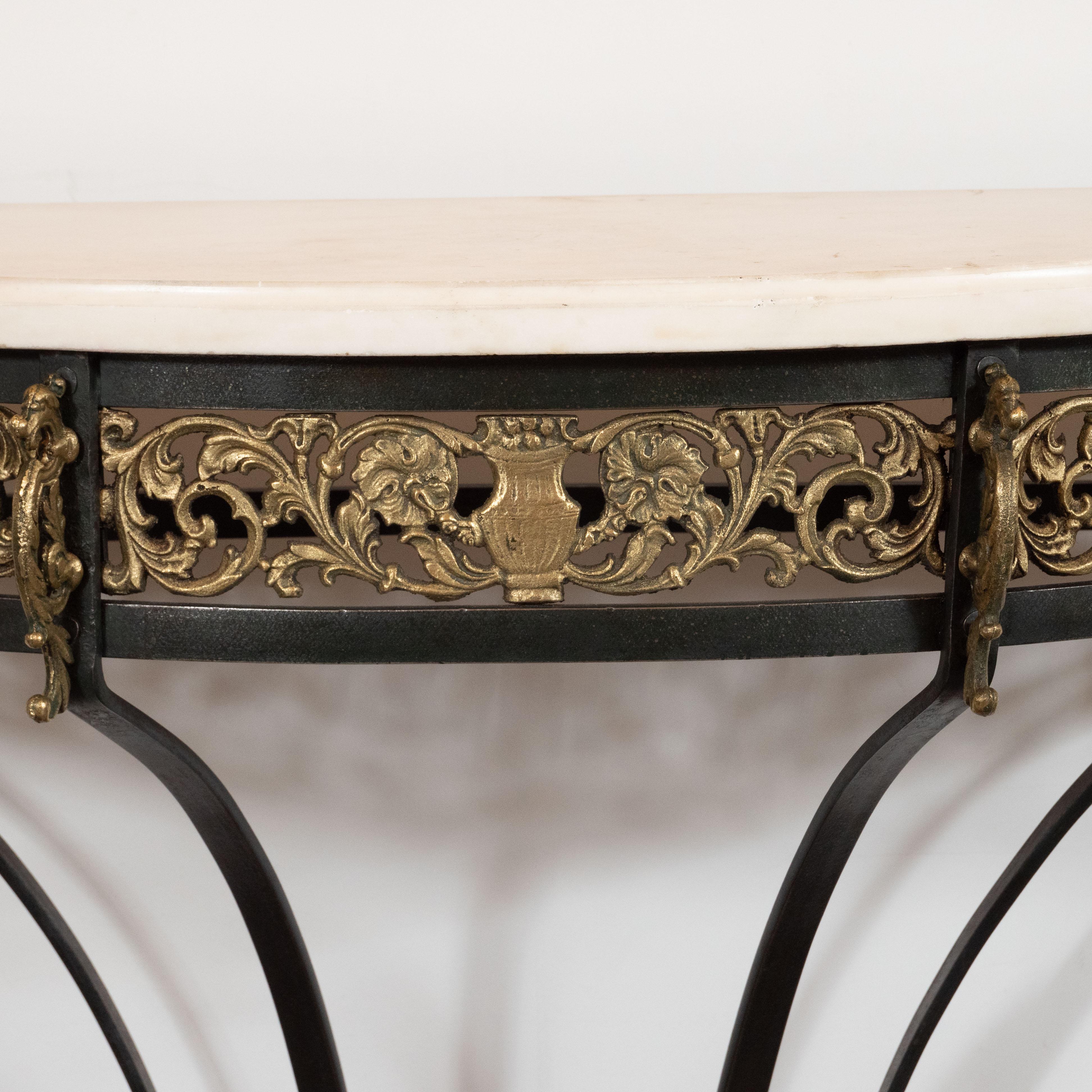This sophisticated Art Deco console table was realized in the United States, circa 1935. Realized in the manner of Edgar Brandt, it features a demilune form Carrara marble top with a subtle grisaille palette and variegated grain. It is supported by