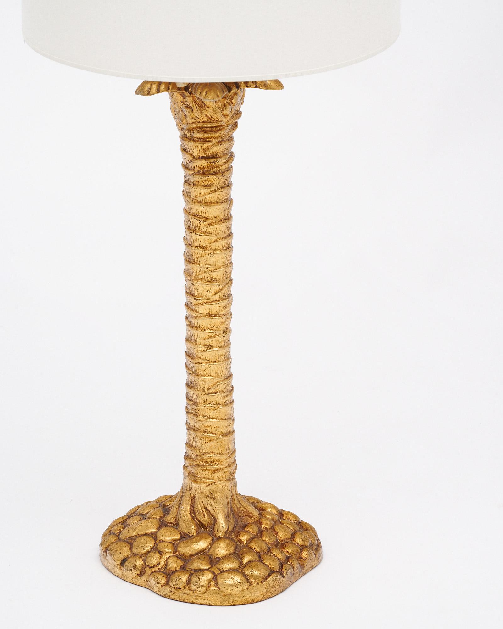Table lamp from the Art Deco period in France. The base of the lamp is made of stuccoed hand carved wood that has been Entirely gold-leafed. The trunk of the tree supports the lamp with the palm leaves at the top. The texture and detail make this a