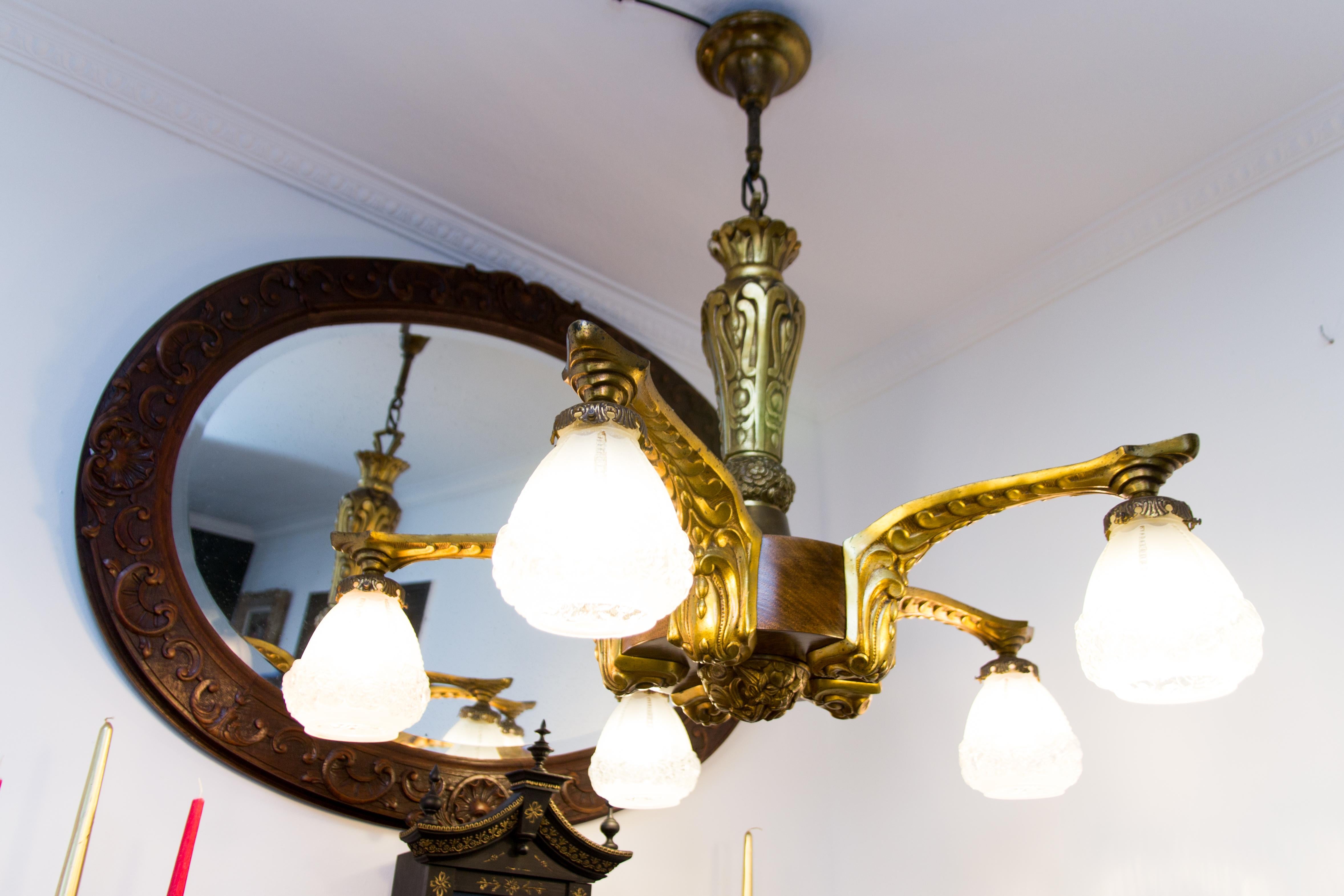 French Art Deco gilt bronze and ashwood chandelier from 1910s. Five bronze arms, each with a frosted floral glass lamp shade and original E27 socket with new wiring.
Bronze parts are decorated with floral motifs.
Measures: Total height is 34.3
