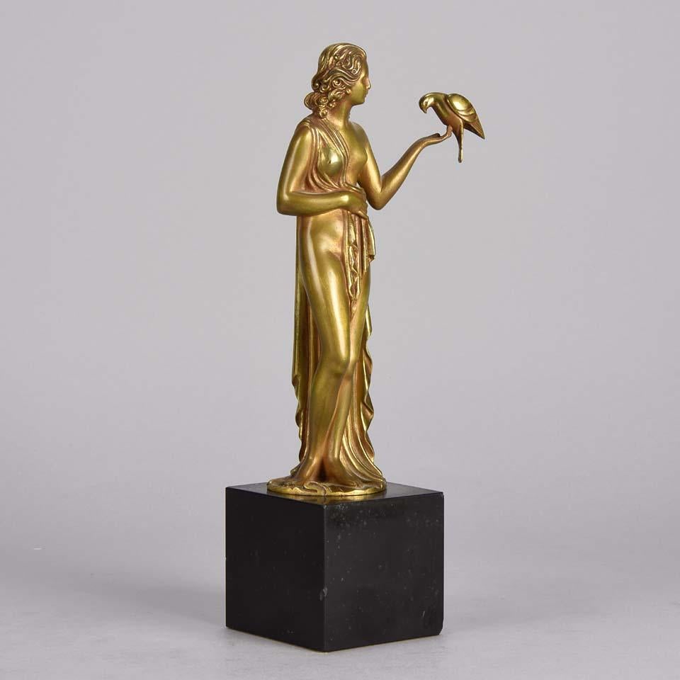 A stunning early 20th century French bronze figure of a semi clad young woman holding a bird in classic high Art Deco pose with excellent gilt patination and intricate surface detail on a square shaped black marble base, signed Pierre Laurel.
 