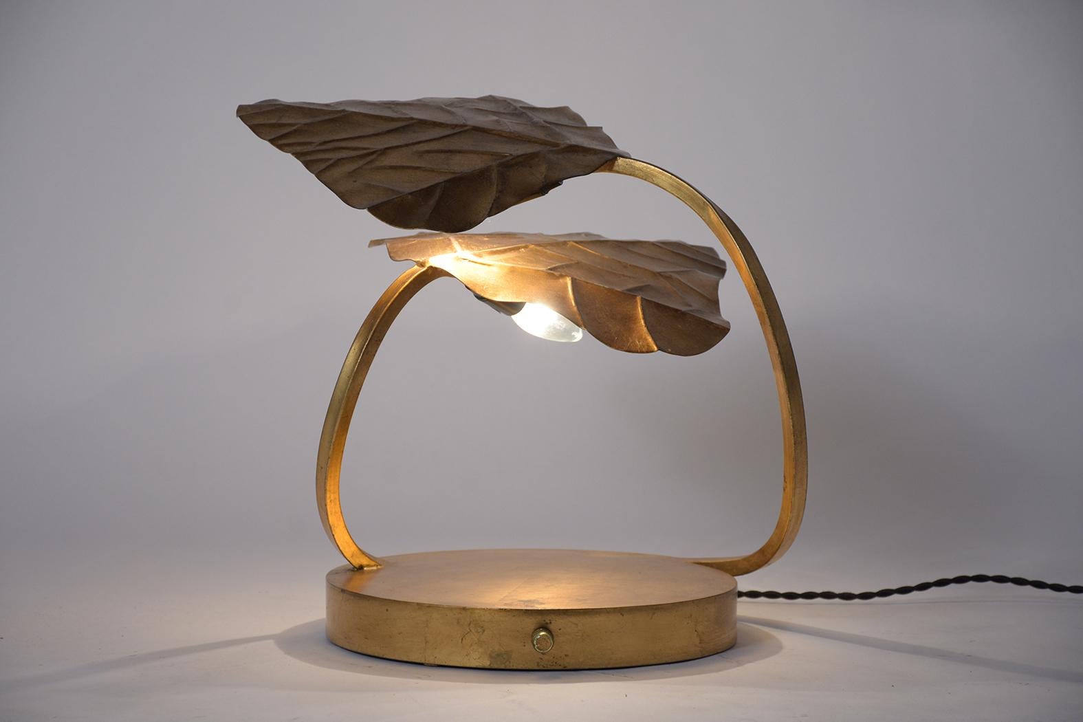 A midcentury-style table lamp in the manner of Tommaso Barbi made out of metal. This lovely lamp features an antique gilt patina finish with unique two leaves design single light for each leaf, is newly wired to US standards, and in working