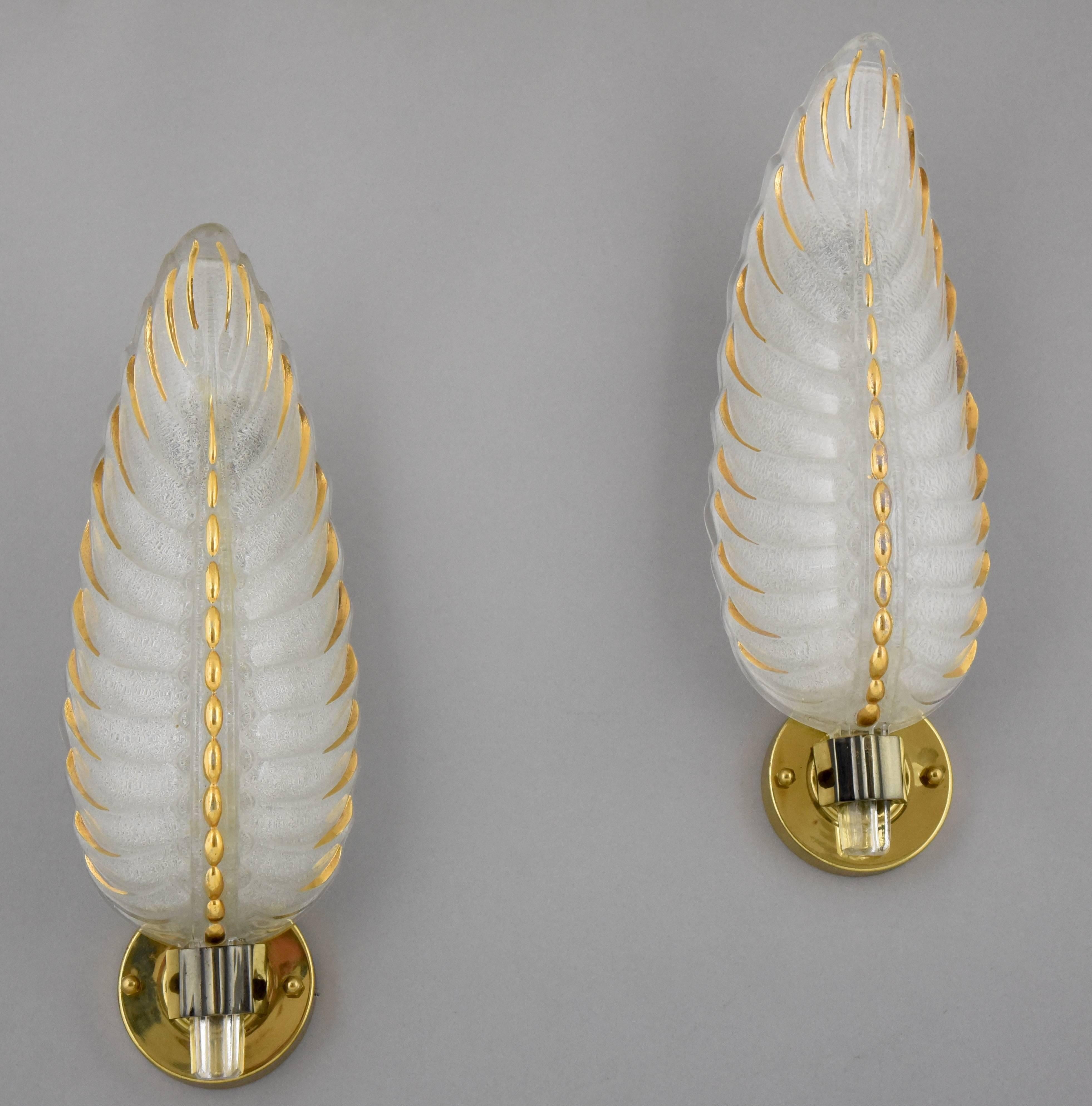 An elegant pair of feather shaped, frosted glass wall sconces with gold accents and a bronze frame signed by Ezan.