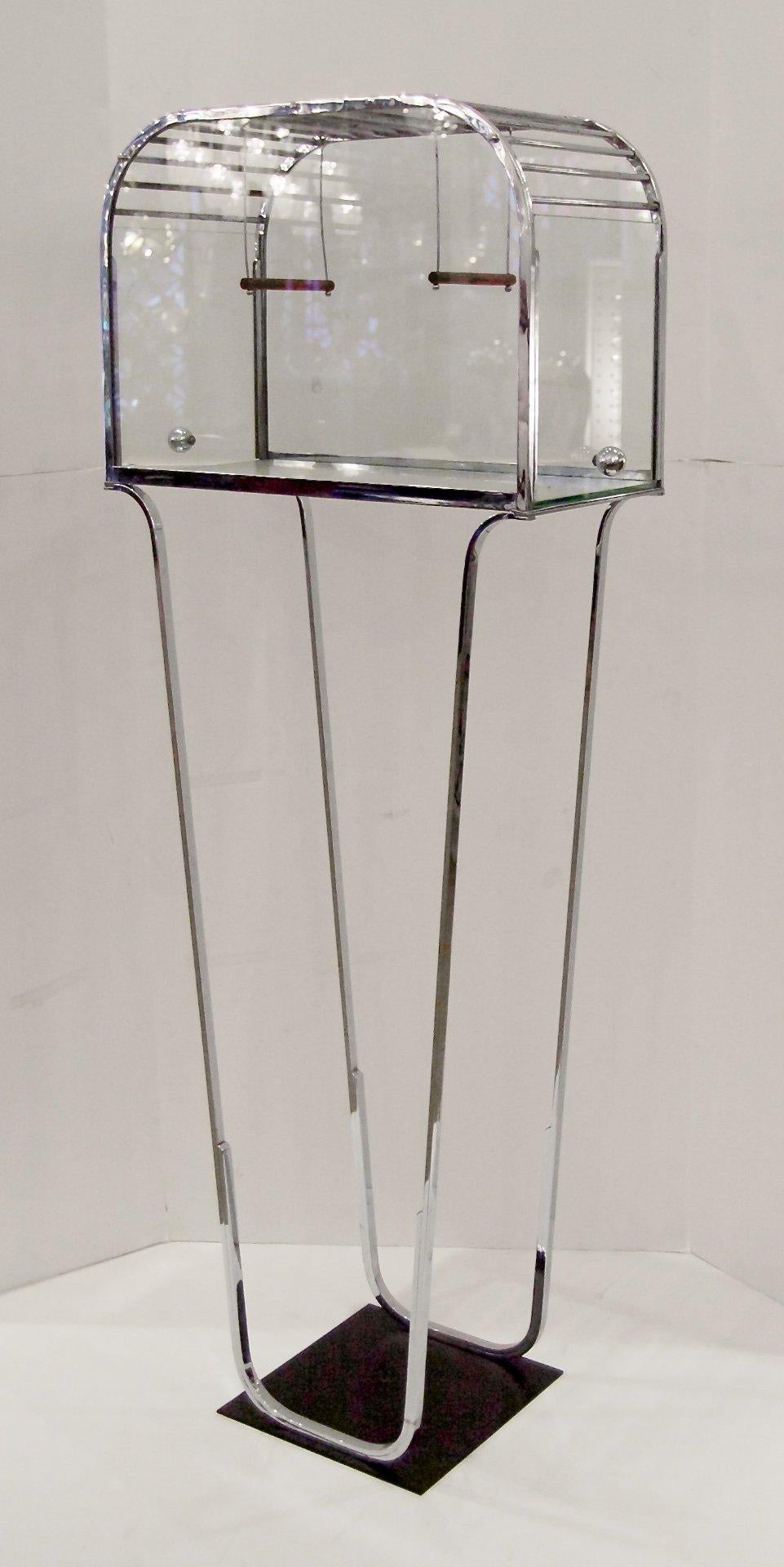 Unique glass and chrome birdcage in distinctive streamline Art Deco style is a whimsical decorative piece. With or without a bird, the piece has a small footprint with crisp chrome details and clear glass for display. Base is enameled black metal.