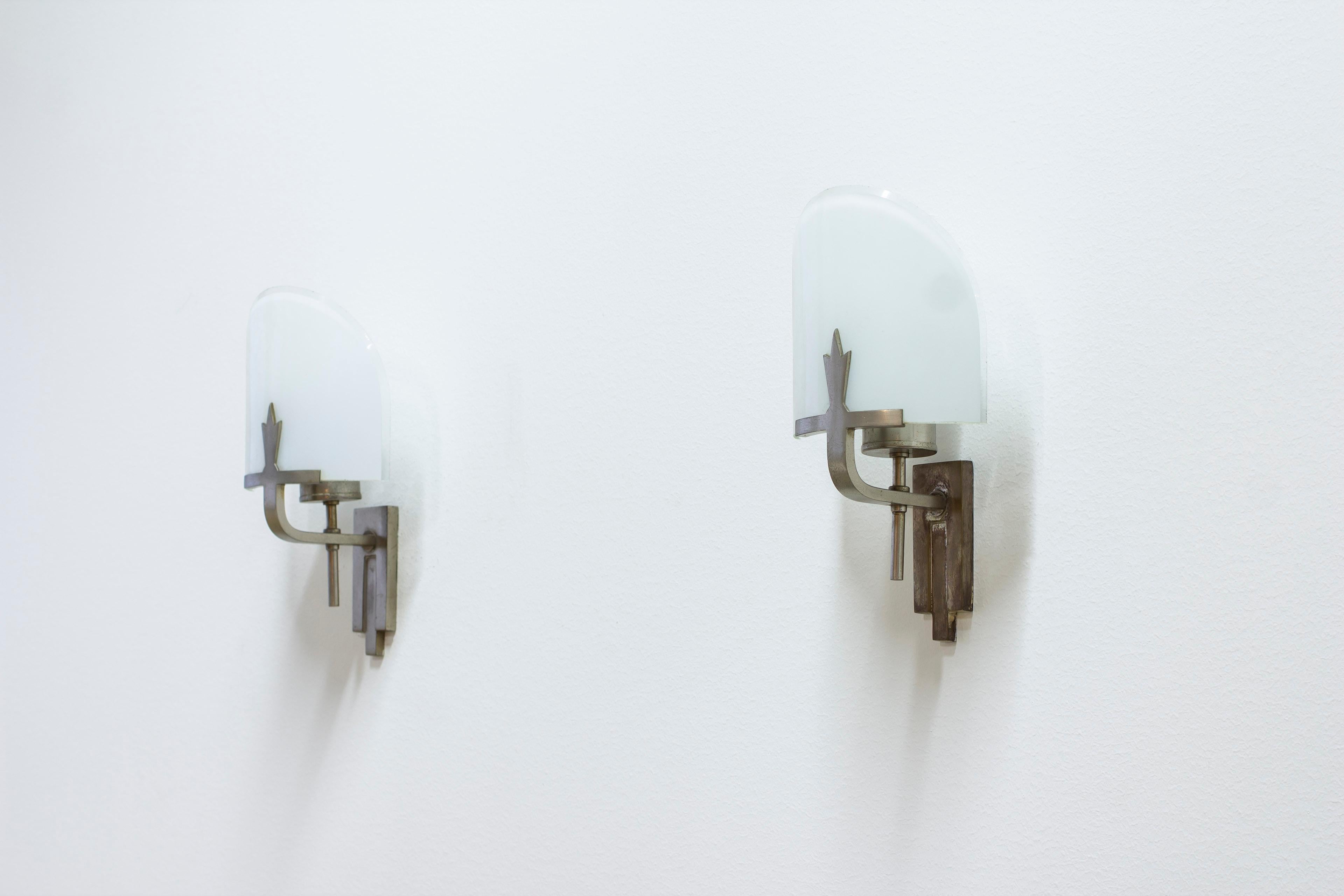 Art deco or Swedish grace wall lamps by unknown maker and designer. Made from nickel plated white metal and opal glass with clear glass rim. Ceramic lamp holder. Good vintage condition with age related wear and patina. 



Price for the pair.

