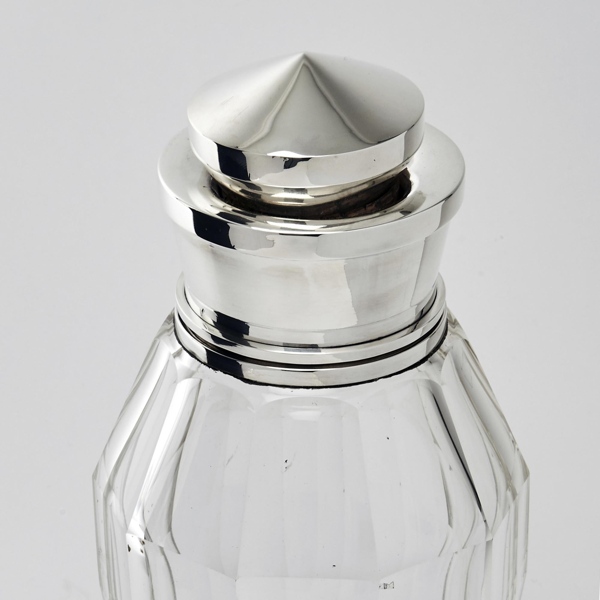 Highly stylized Art Deco style cocktail shaker in a design so reminiscent of the period. The body is handcut glass while the stopper and collar are sterling silver. This piece was made in France for the English market and bears London import