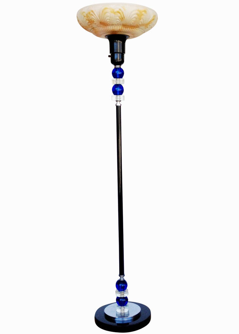 Black enameled Art Deco torchiere floor lamp with decorative blue and clear glass accents made complete with a large chromed steel accent along the base. This lamp is designed with a mogul base bulb and dispenses 100W/200W/300W using a three way