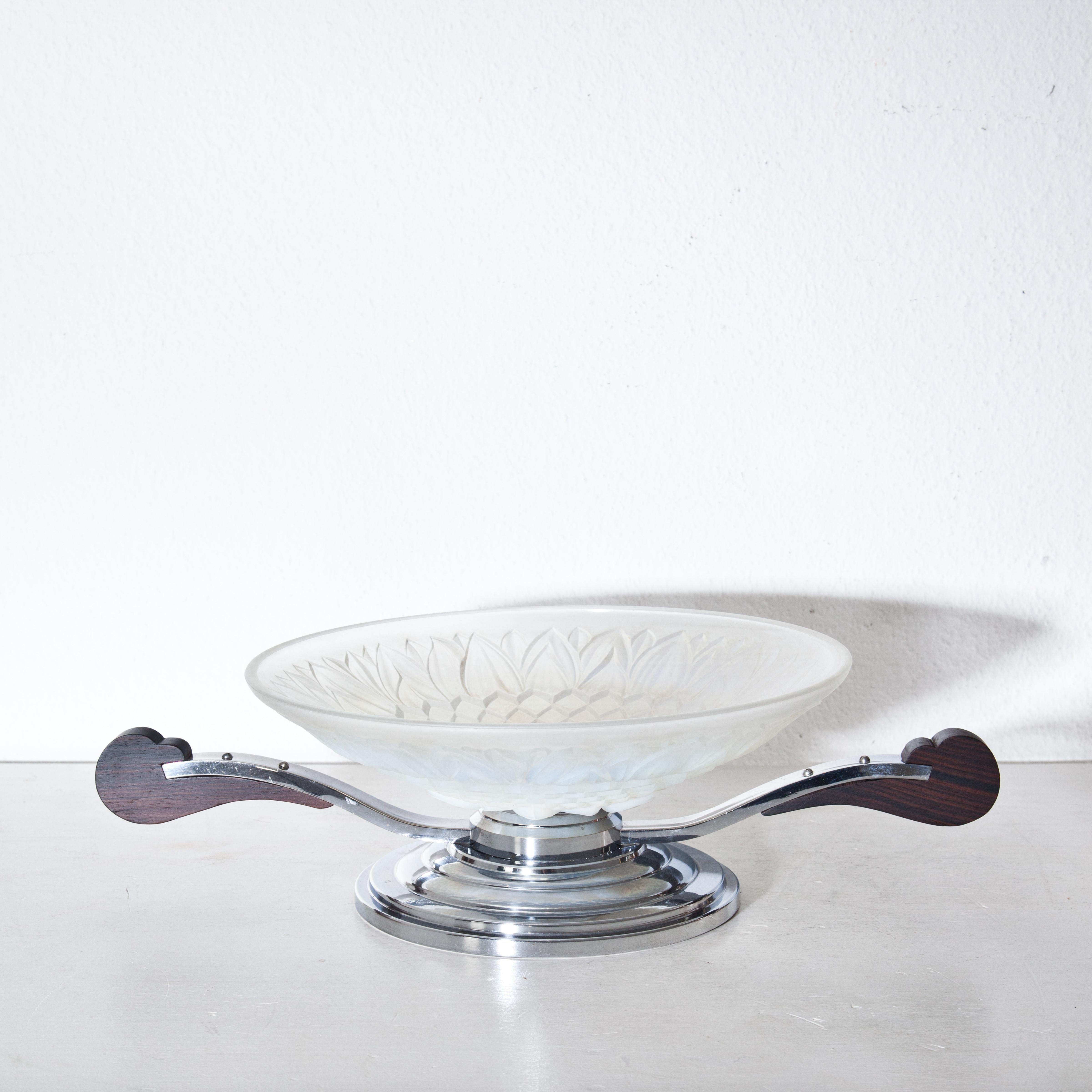 Art Deco bowl standing on a round base with glass insert and wooden handles. The wall is decorated with leaf decorations in relief.