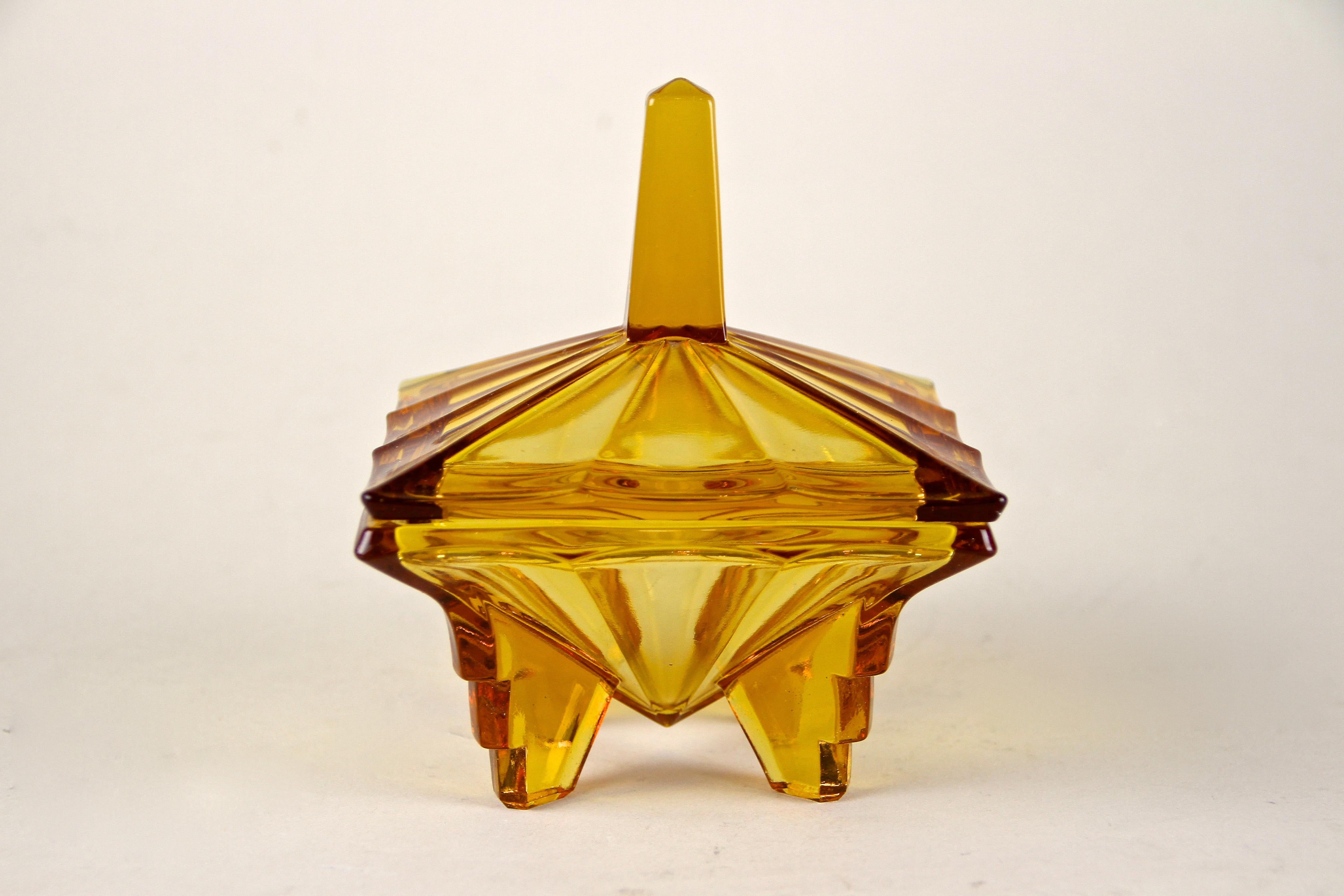 Exclusive Art Deco glass box with lid from the period in Austria, circa 1920. This highly decorative, amber colored pressed glass box impresses with an absolute unique shape, reflecting the famous Art Deco form language at its best. A great designed