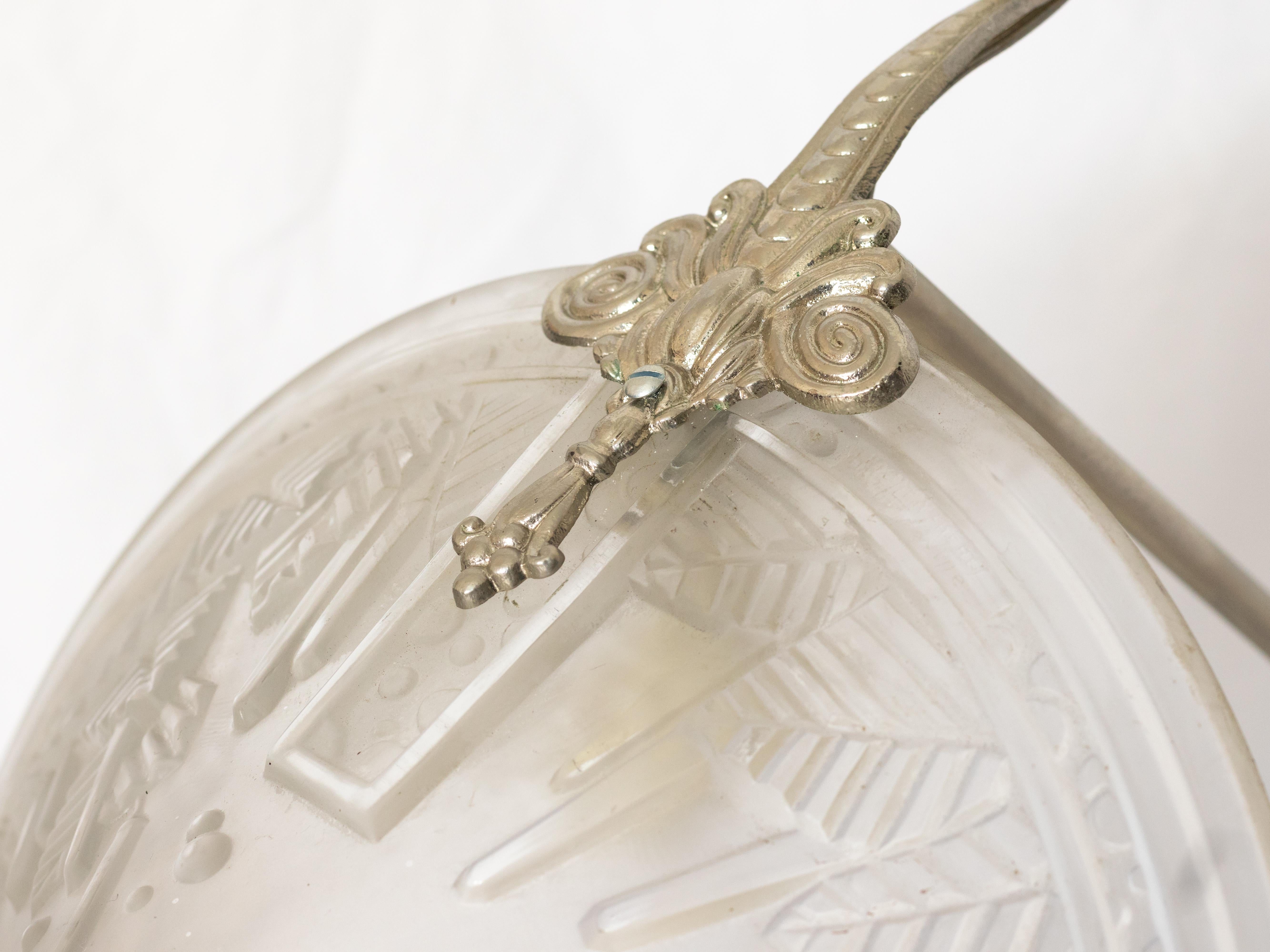 This French Art Deco chandelier signed by Muller showcases the artistry and elegance of early 20th-century French design. 
Crafted in frosted glass with intricate geometric patterns and stylized natural forms, it features a graceful three-arm
