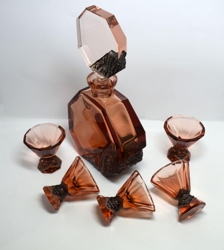 For your consideration is this fabulous Art Deco decanter set with 5 matching glasses is intricately detailed facet-cut glass with acid mat relief panels in a amber rose glass, manufactured by Curt Schlevogt, who established his own glass company in