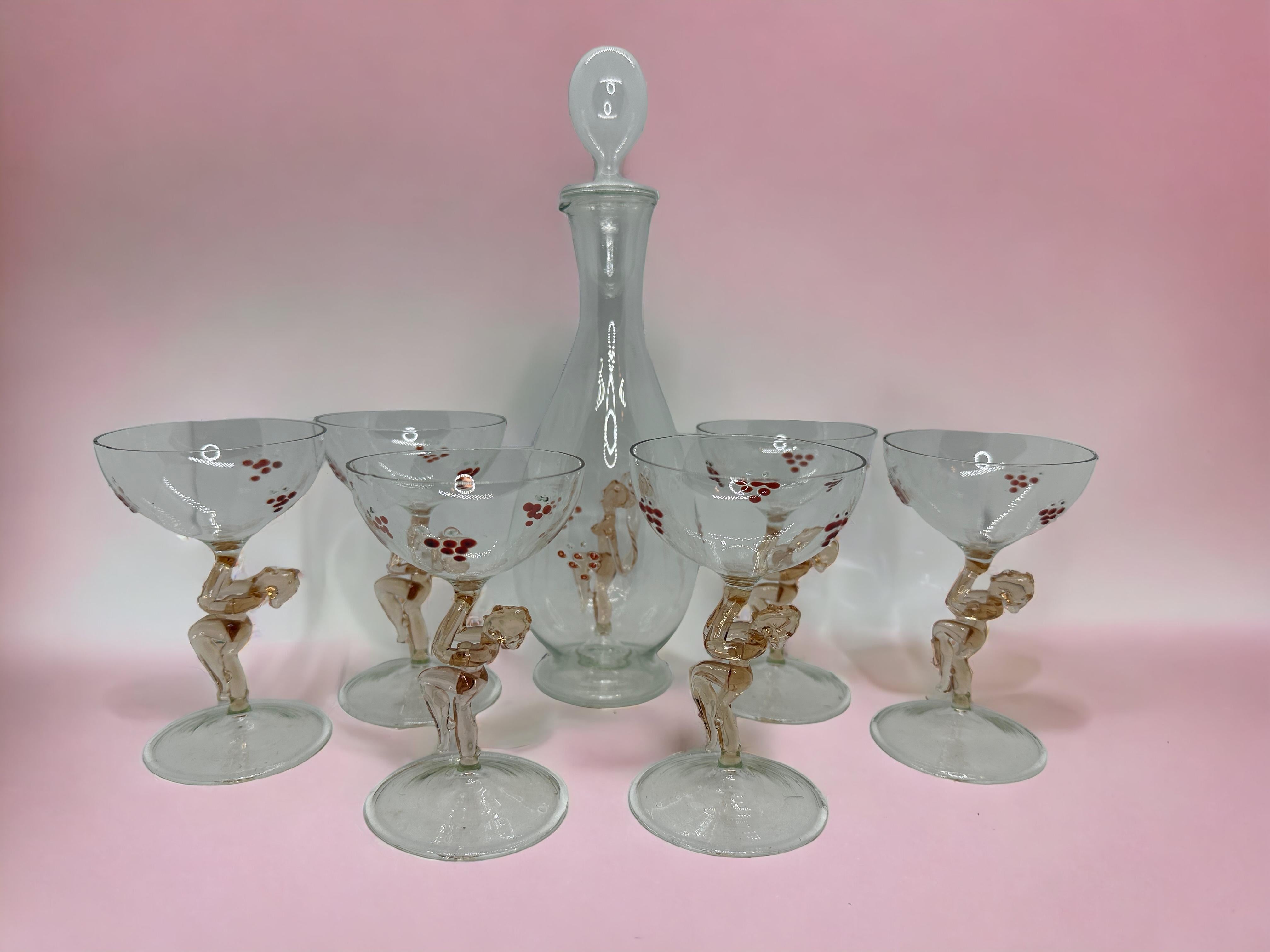 
A slightly cheeky Art Deco decanter set with matching set of six glasses in handblown clear glass, in the style of Bimini. The stems designed as nude ladies. In beautiful pastel colors. Very delicate to touch and amazing that something like this