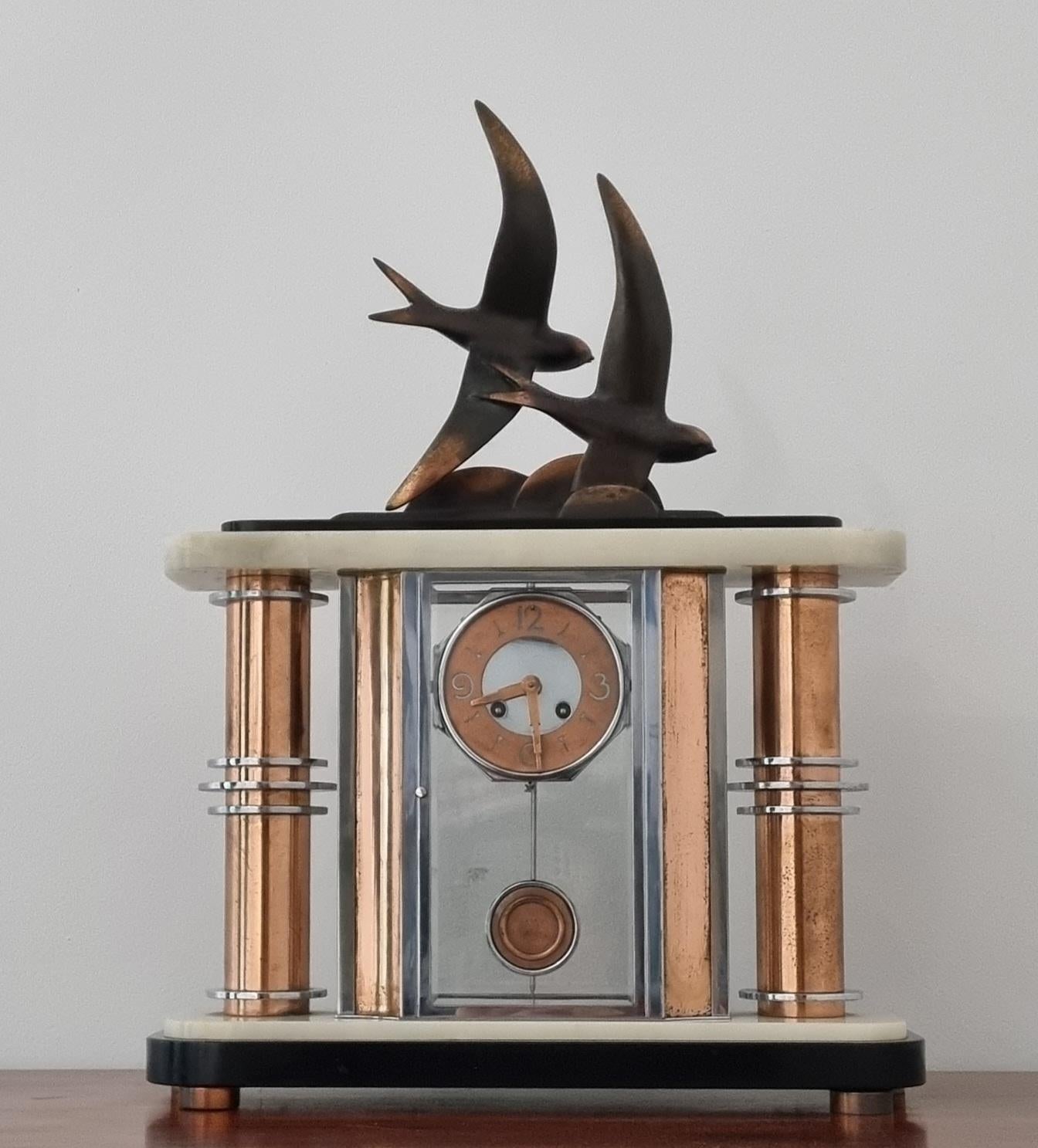 A striking Art Deco Cubist design clock featuring a mirrored face framed by chrome and copper-plated elements, crowned with intricate bronze shallows. This piece embodies the sleek, modernist design typical of the Art Deco era, making it a versatile