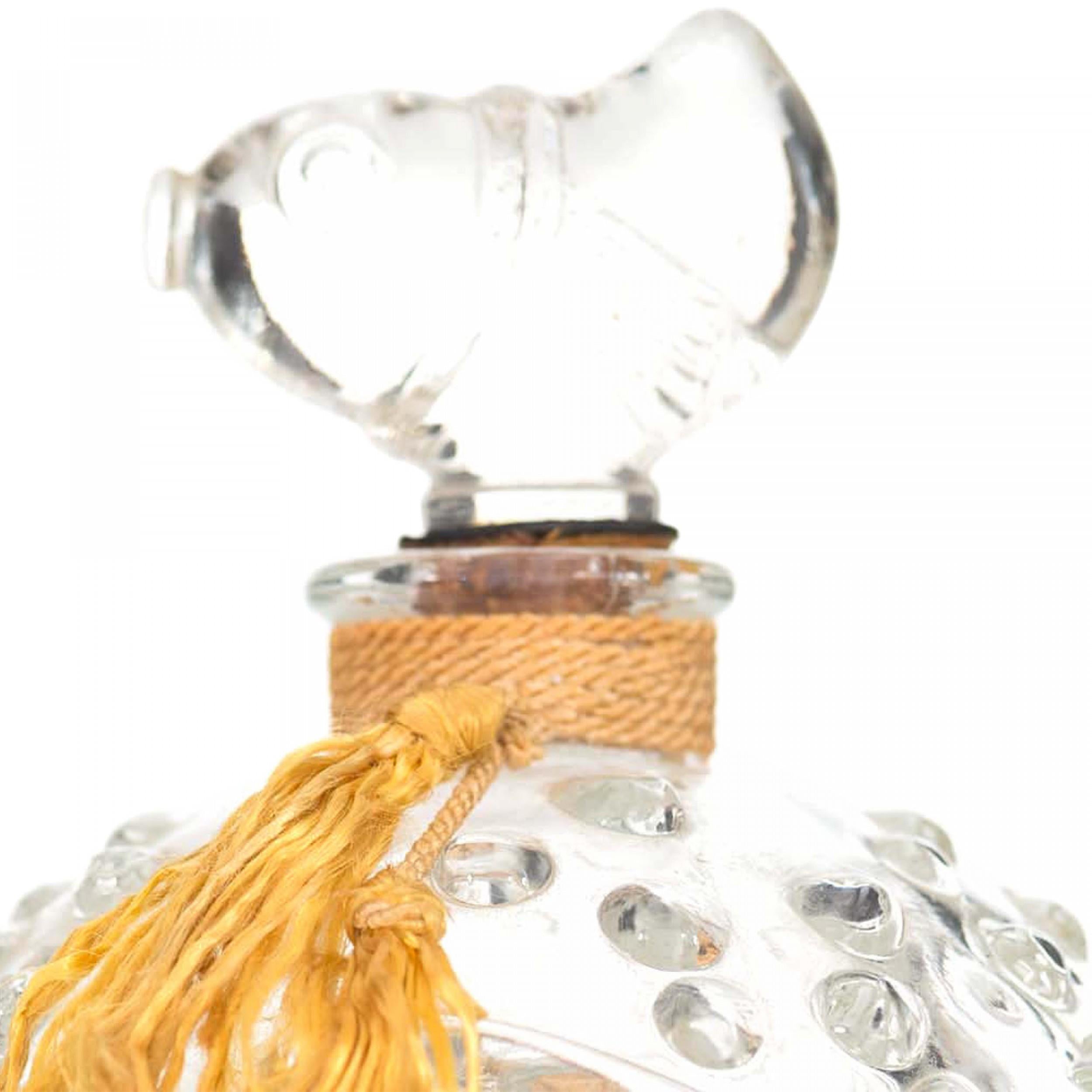 Parfümflakon aus Klarglas (THE THEON CO.) in Kugelform im Art-déco-Stil mit geprägtem Wellen- und Blasenmotiv, goldener Quaste am Hals und fischförmigem Stopfen.