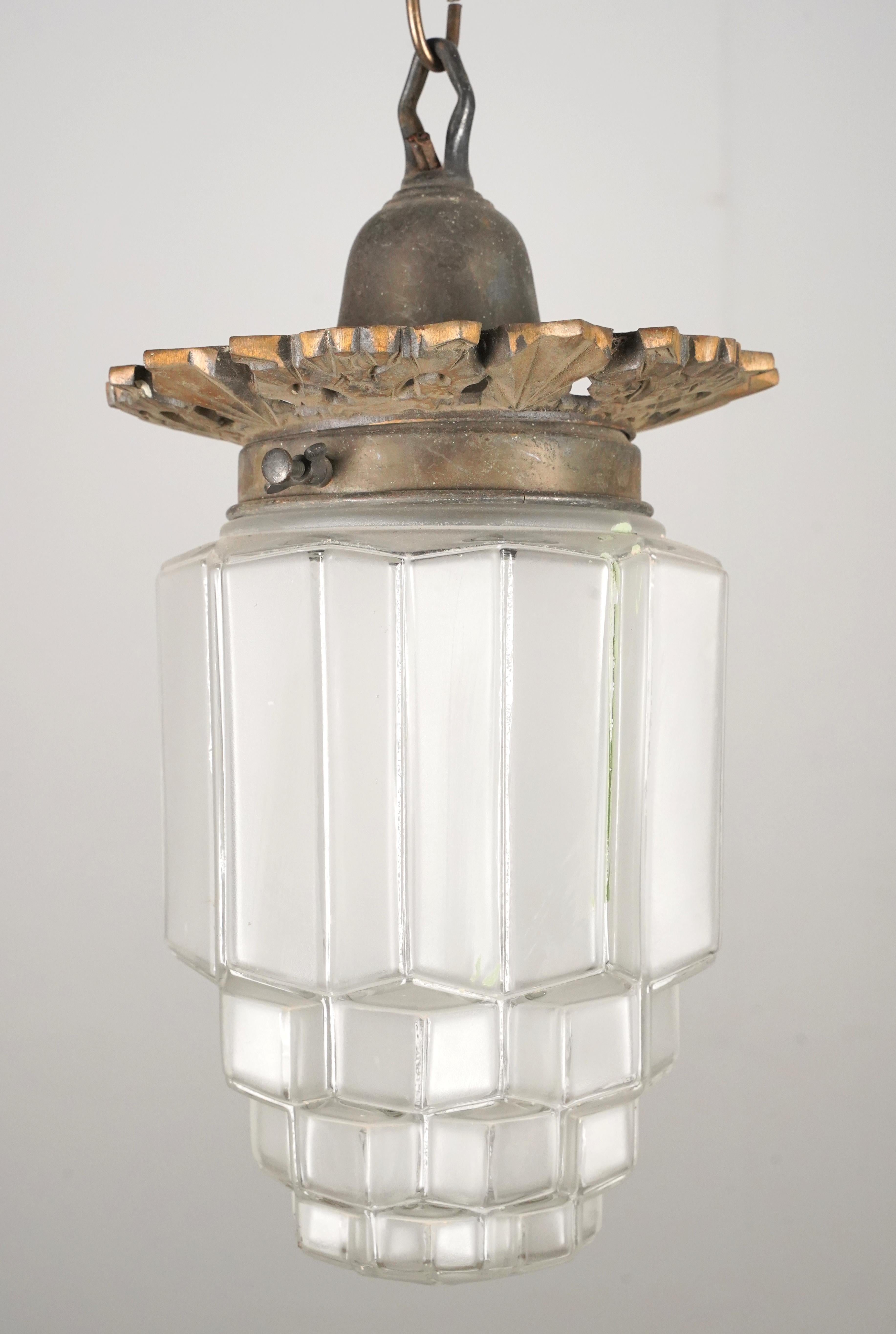 Lampada a sospensione in stile Art Déco composta da un globo smerigliato a forma di grattacielo abbinato a una catena in ottone antico. La catena con finitura in ottone è realizzata in acciaio. Richiede una lampadina standard di tipo Edison a base