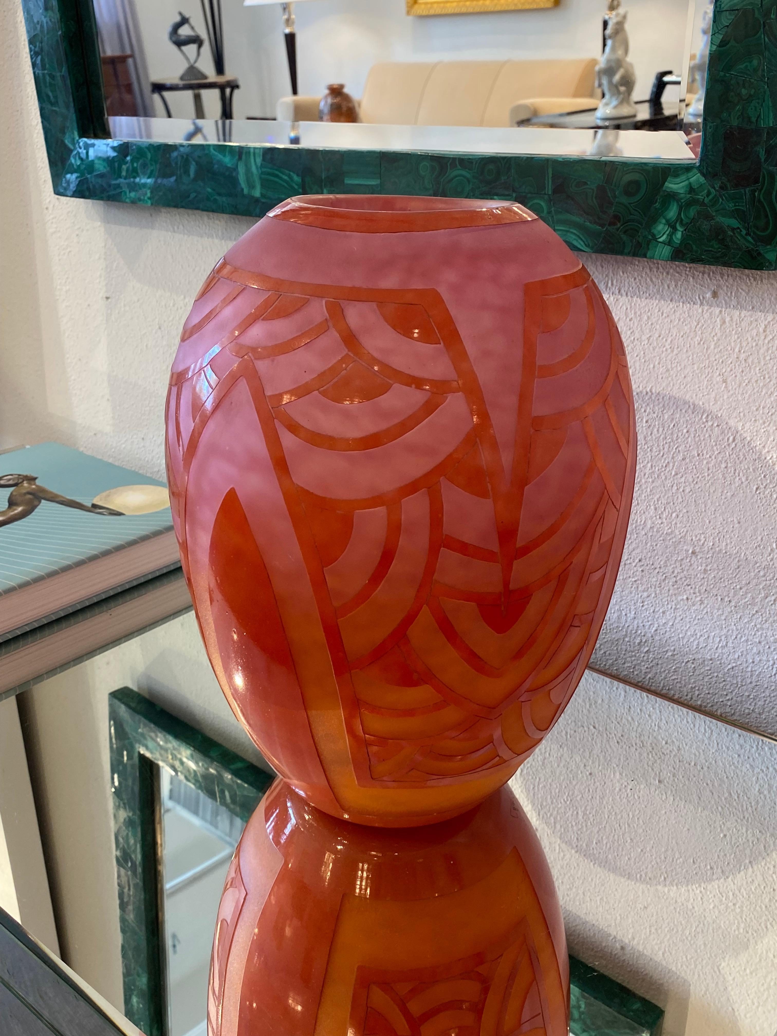 A cylindrical-rounded glass vase with a Degradé of Pink-Orange background.  The geometric design is in Red.  The Nénnuphar Rouge is one of the most desirable pattern of Le Verre Français.  The pattern is acid-etched.
Signature: Le Verre Francais -