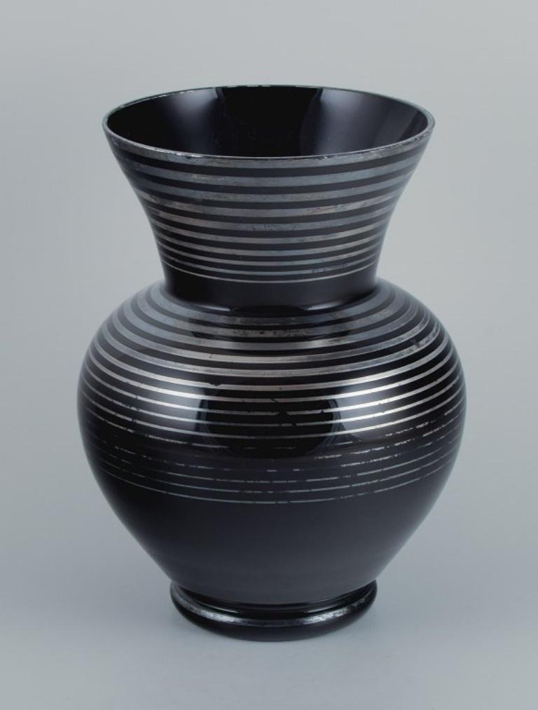 Vase en verre Art déco, Allemagne. Avec incrustations horizontales en argent.
1930/40s.
En excellent état avec une usure mineure.
Dimensions : H 27,0 x P 17,0 cm : H 27,0 x D 17,0 cm.