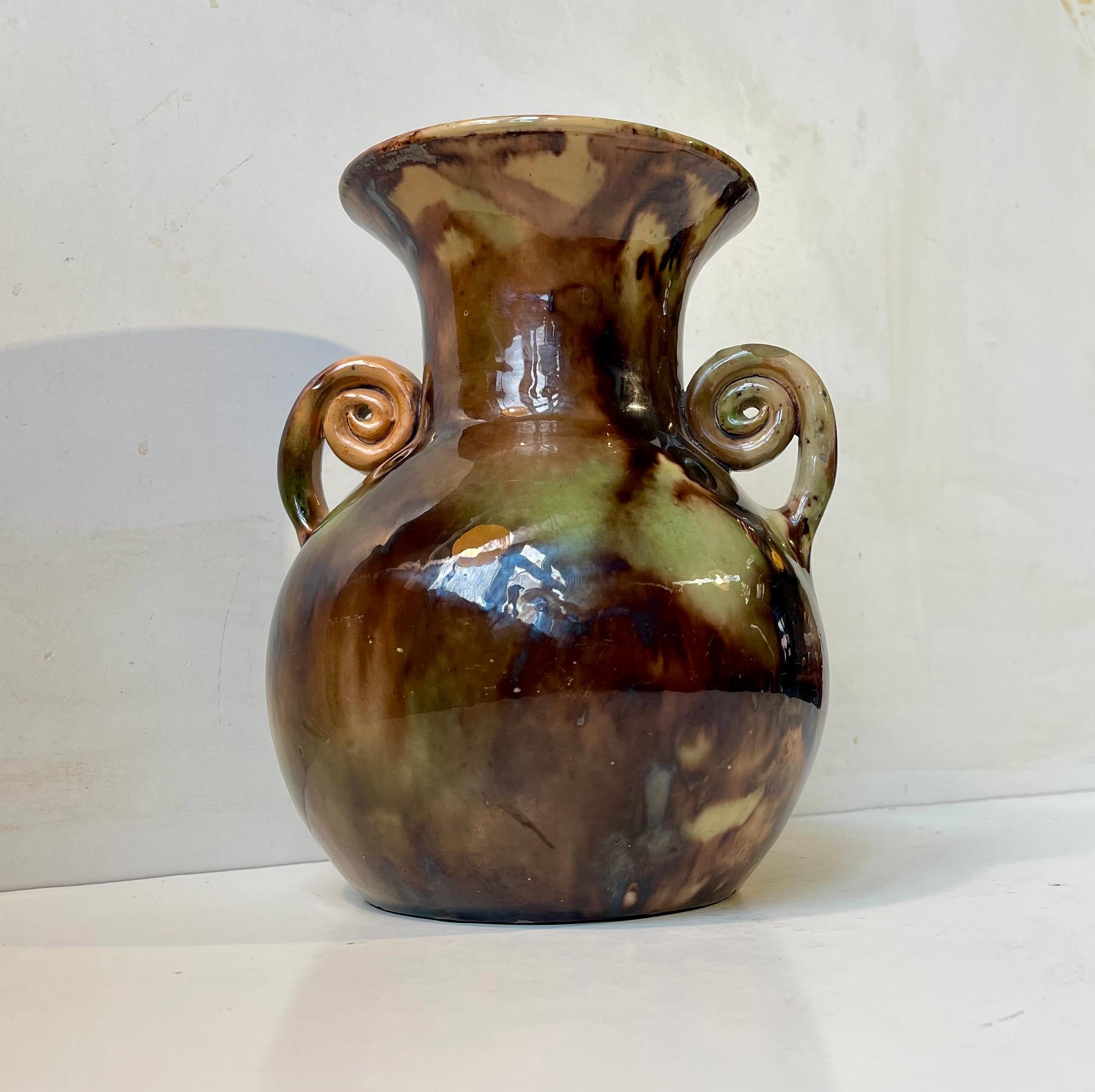 Art Deco ceramic vase with Majolica camouflage glaze and swirling handles. Designed and made around 1920 by Michael Andersen & Son on the island of Bornholm in Denmark. Measurements: H: 23 cm, Diameter: 13 cm (top/neck).