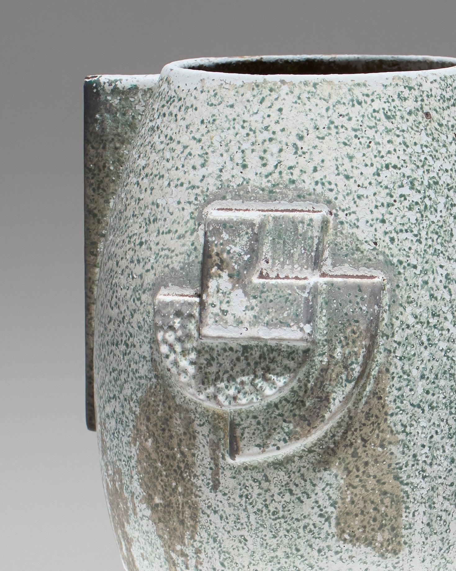 Vase Art Deco en céramique émaillée et fonte de fer, teinte bleu/vert, ornés de motifs géométriques en relief. Texture légèrement brute, aspect et usure du revêtement normaux. Une fissure est présente sur le coté du vase. En bel état.