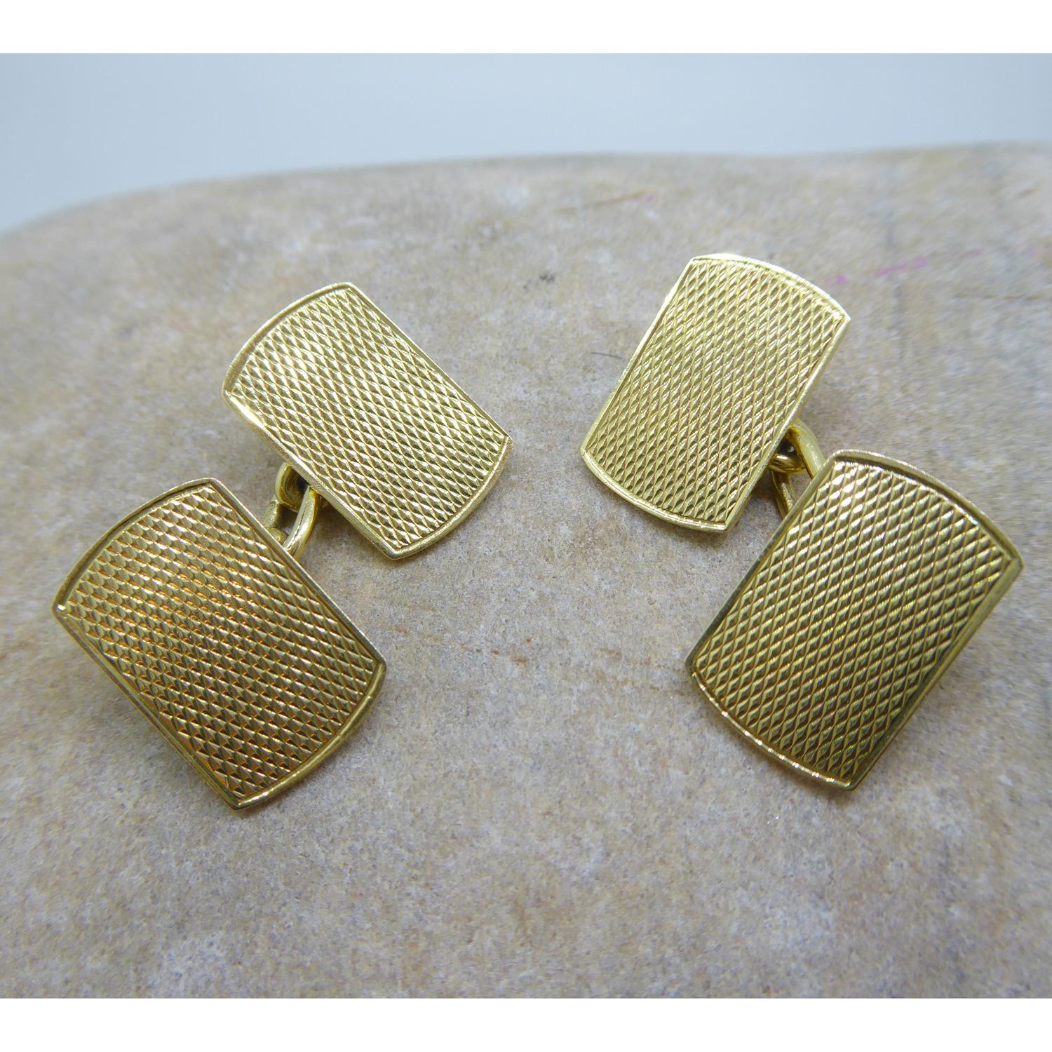 From the Art Deco era, a pair of 18ct yellow gold cufflinks hallmarked London 1931.  Machine engraved with diamond pattern within a reeded border, the cufflinks are overall rectangular shape with D shaped ends and are connected by oval link gold