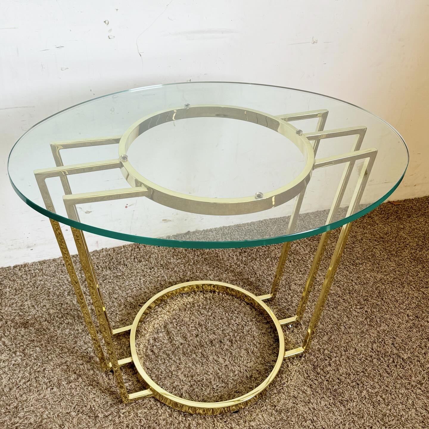 Plongez dans l'élégance de l'ère Art déco avec cette table d'appoint à plateau de verre ovale doré. La table est dotée d'un cadre doré aux lignes géométriques audacieuses et d'un plateau ovale en verre qui met en valeur le design complexe de la