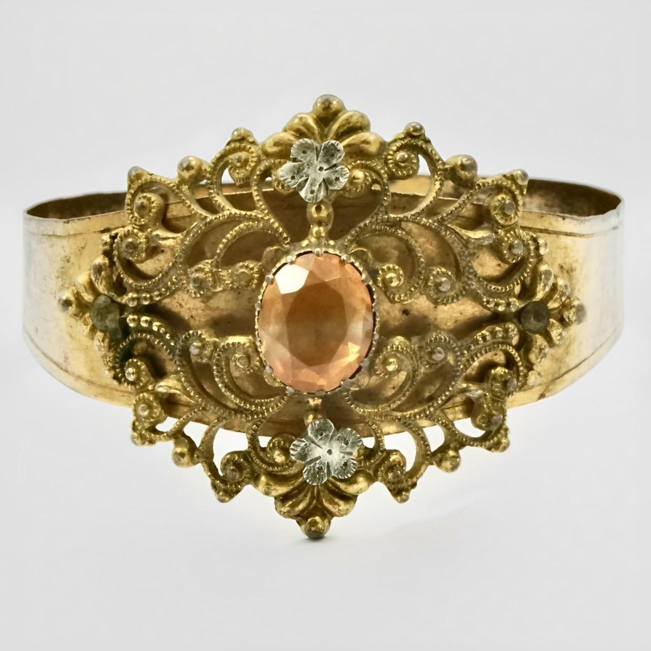 Beautiful Art Deco gold plated filigree bangle bracelet, set with an amber paste stone and two silver tone flowers. The bangle is adjustable, measuring inside diameter approximately width 5.7 cm / 2.24 inches to 6.1 cm / 2.4 inches. The width at the
