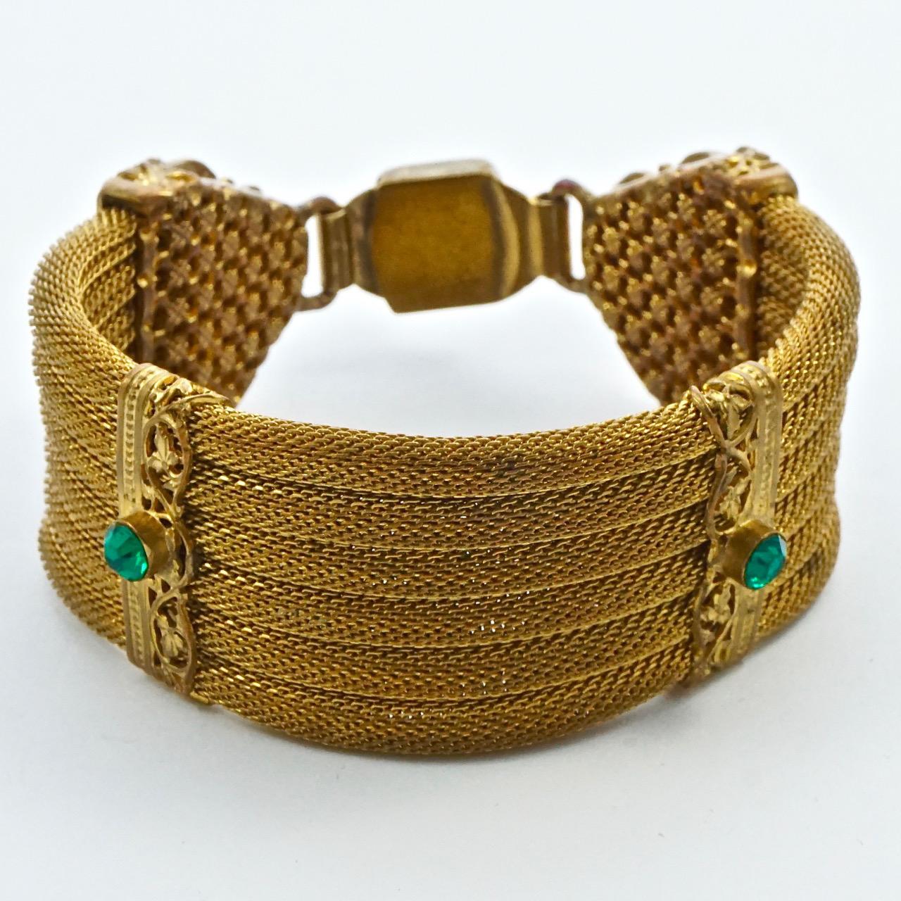 Art Deco gold plated mesh bracelet, featuring green rhinestone and green cabochon jewels, and ornate metalwork. It is probably Czech in origin. Measuring length 17.8cm / 7 inches by width 2.6cm / 1 inch. There is wear to the gold plating.

This very