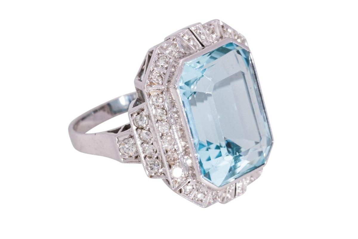 Art Déco style ring with an octagonal faceted aquamarine weighing approx. 12.00 ct, with a beautiful blue color. Set and surrounded by 34 diamonds with a total weight of approx. 0.60 ct. Ring made of 14-carat white gold.

Product weight: 8.43