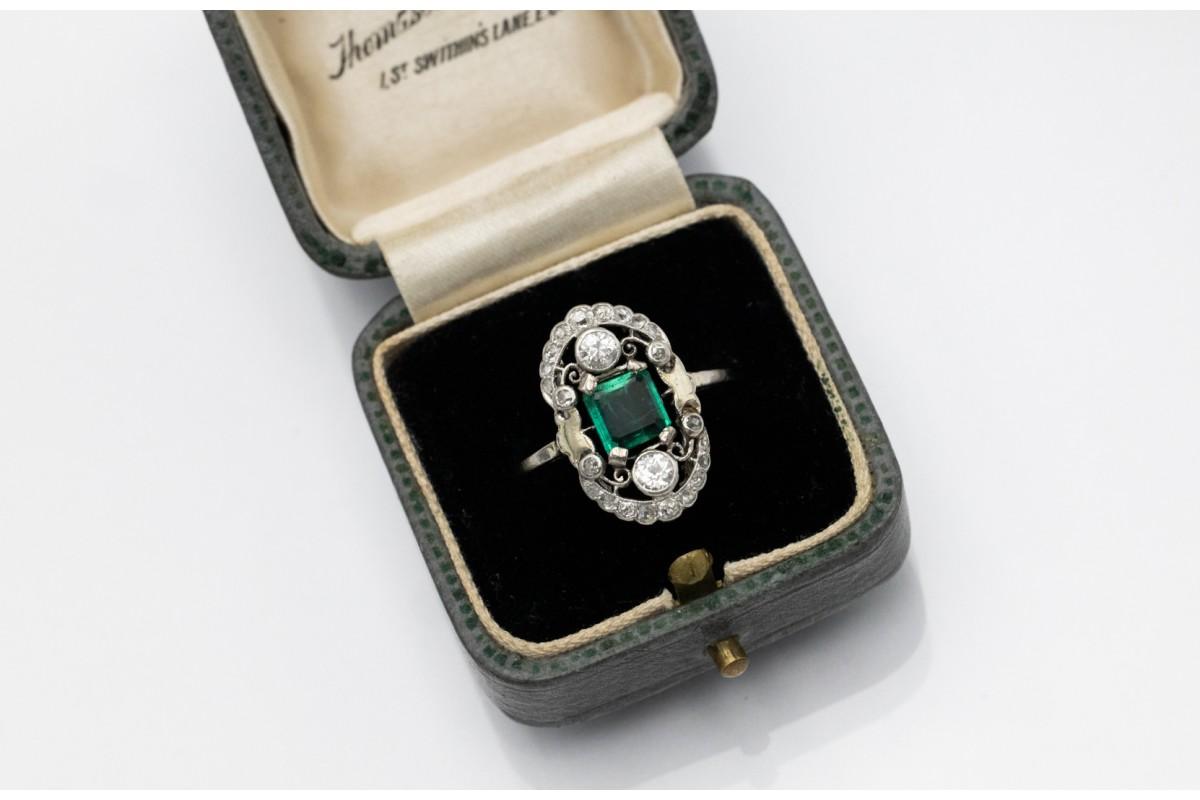 Une bague unique en or blanc 18 carats (titre 0,750) et en platine.

La bague est ornée d'une émeraude carrée à facettes d'une belle couleur verte avec des inclusions naturelles pesant environ 0,60 ct. En outre, la bague est ornée de 2 diamants en