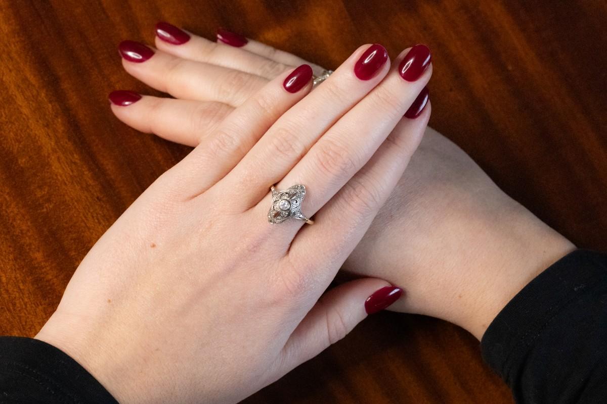 Ein einzigartiger Art-Déco-Ring mit Diamanten. Hergestellt aus 14-karätigem Weiß- und Gelbgold (Feingehalt 585). Die durchbrochene Form des 19 mm hohen Rings ist mit einem alten Diamanten im Brillantschliff von ca. 0,10 ct und 10 Diamanten im
