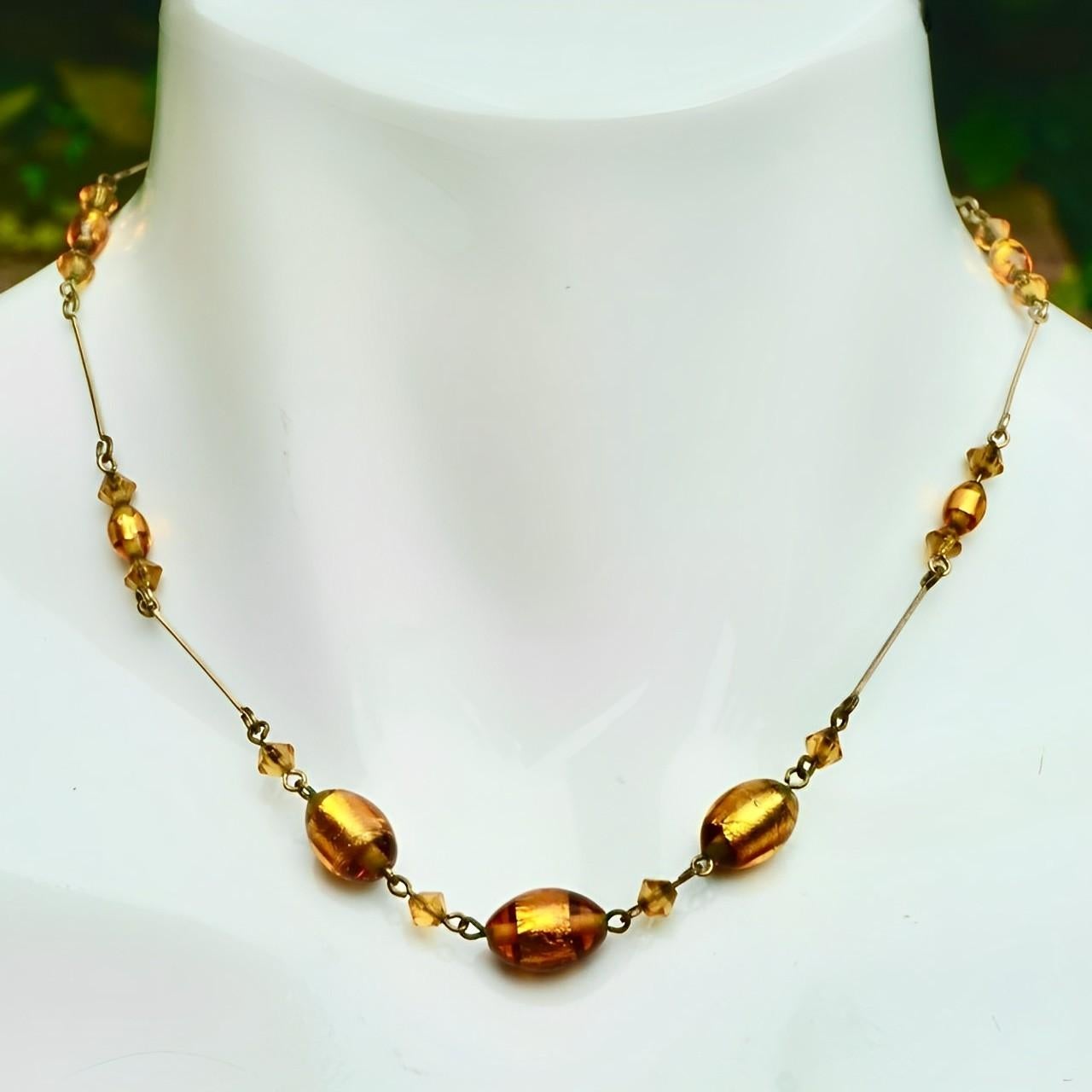 Wunderschöne goldfarbene Art-Déco-Drahtkette mit ovalen Glasperlen mit Goldfolie und goldenen Glasperlenakzenten. Länge 41,3 cm / 16,25 Zoll.

Diese schöne Halskette aus goldenem Folienglas stammt aus den 1930er Jahren.