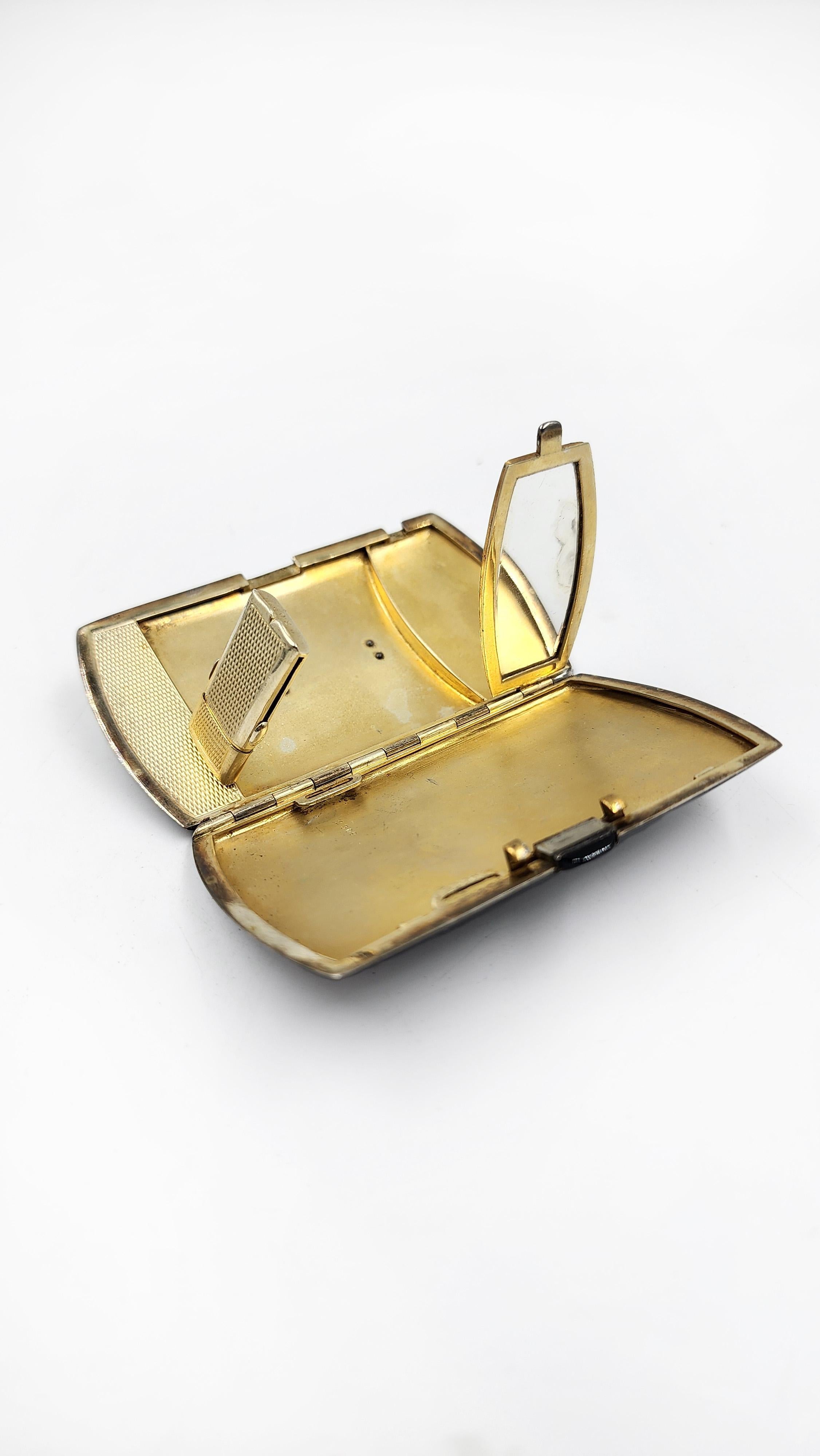 Art Deco Vanity Case in Gold with Black Enamel and Jade Decoration
This Art Deco vanity case features a rectangular shape with rounded edges and a glossy black enamel exterior finish. The top of the lid is adorned with a rectangular, veined jade
