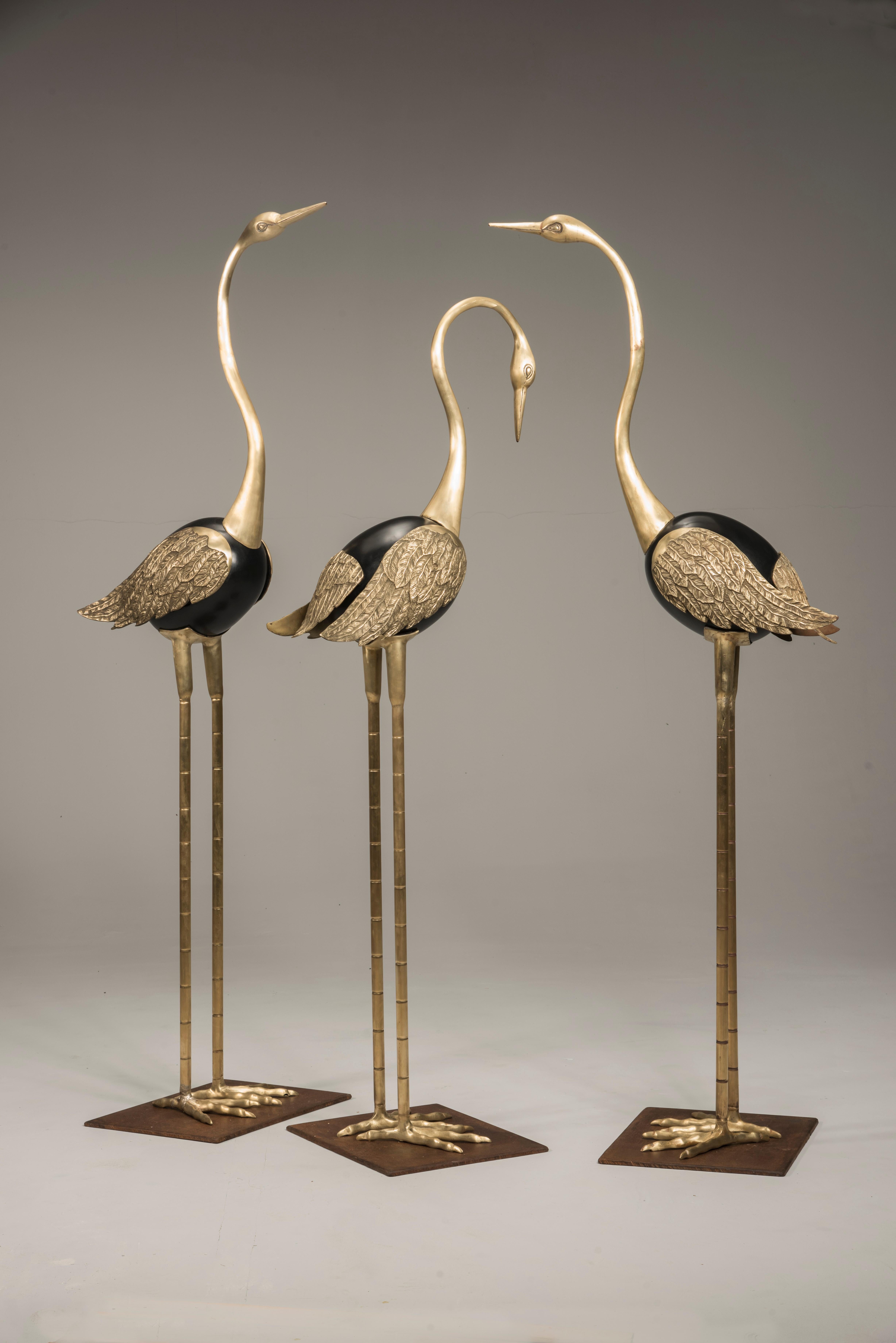 Three Italian Art Deco sculptures representing standing flamingos with three different poses of the head and the neck. They are made of brass, with central rounded body lacquered in black. The wings are finely worked with feathers effect. They have