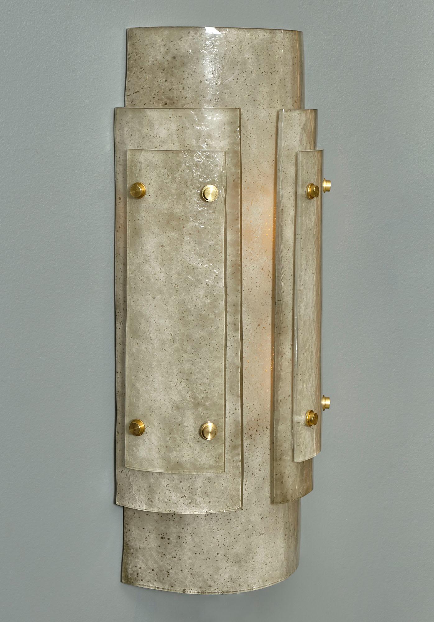 Pareja de apliques Art Decó de cristal de Murano gris procedentes de Italia. Estos apliques presentan tres gruesas capas de cristal gris moteado ahumado y texturizado; superpuestas sobre una sólida estructura de latón. Un magnífico conjunto de luces
