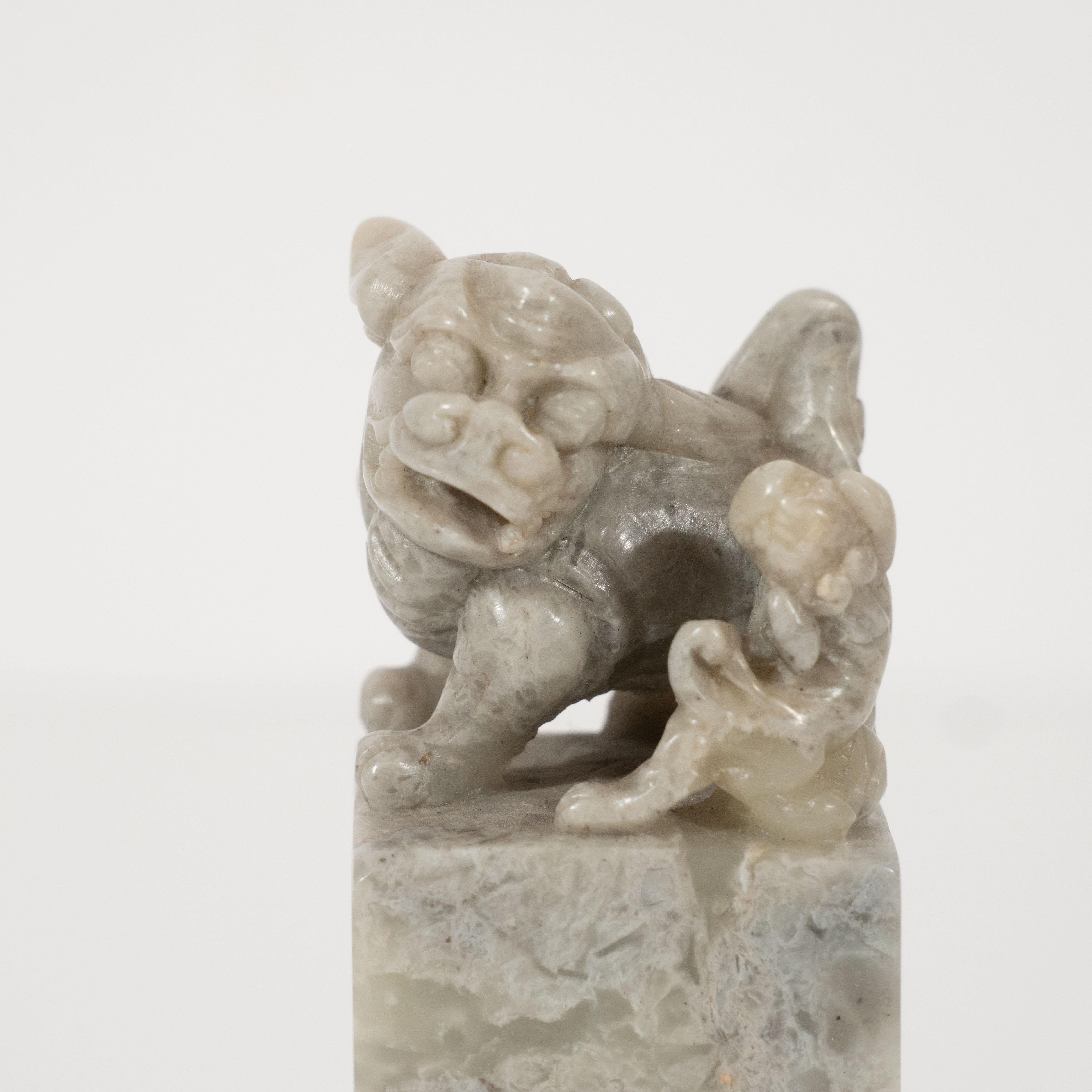 This beautiful Art Deco stamp was realized in China, circa 1925. It features a volumetric rectangular body crowned with a hand carved guardian lion (a Chinese leitmotif) and accompanying pup, climbing its hind leg- all realized in gray stone,