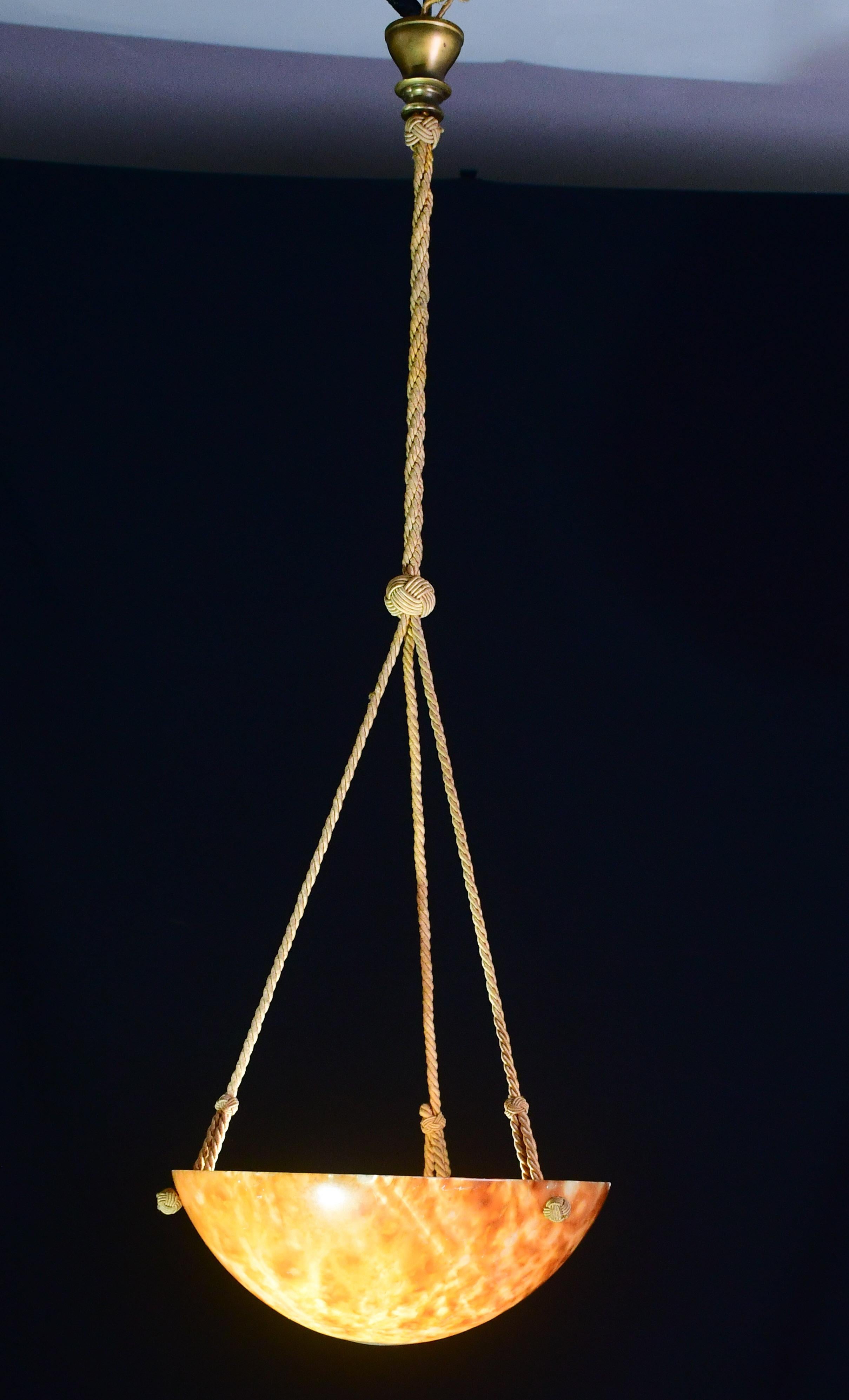 Lustre antique en albâtre brun de style Art D�éco, vers les années 1940.
Une pièce unique en albâtre orange, magnifiquement travaillée avec des teintes et des reflets d'autres couleurs lorsqu'elle est éclairée, toujours suspendue aux trois chaînes