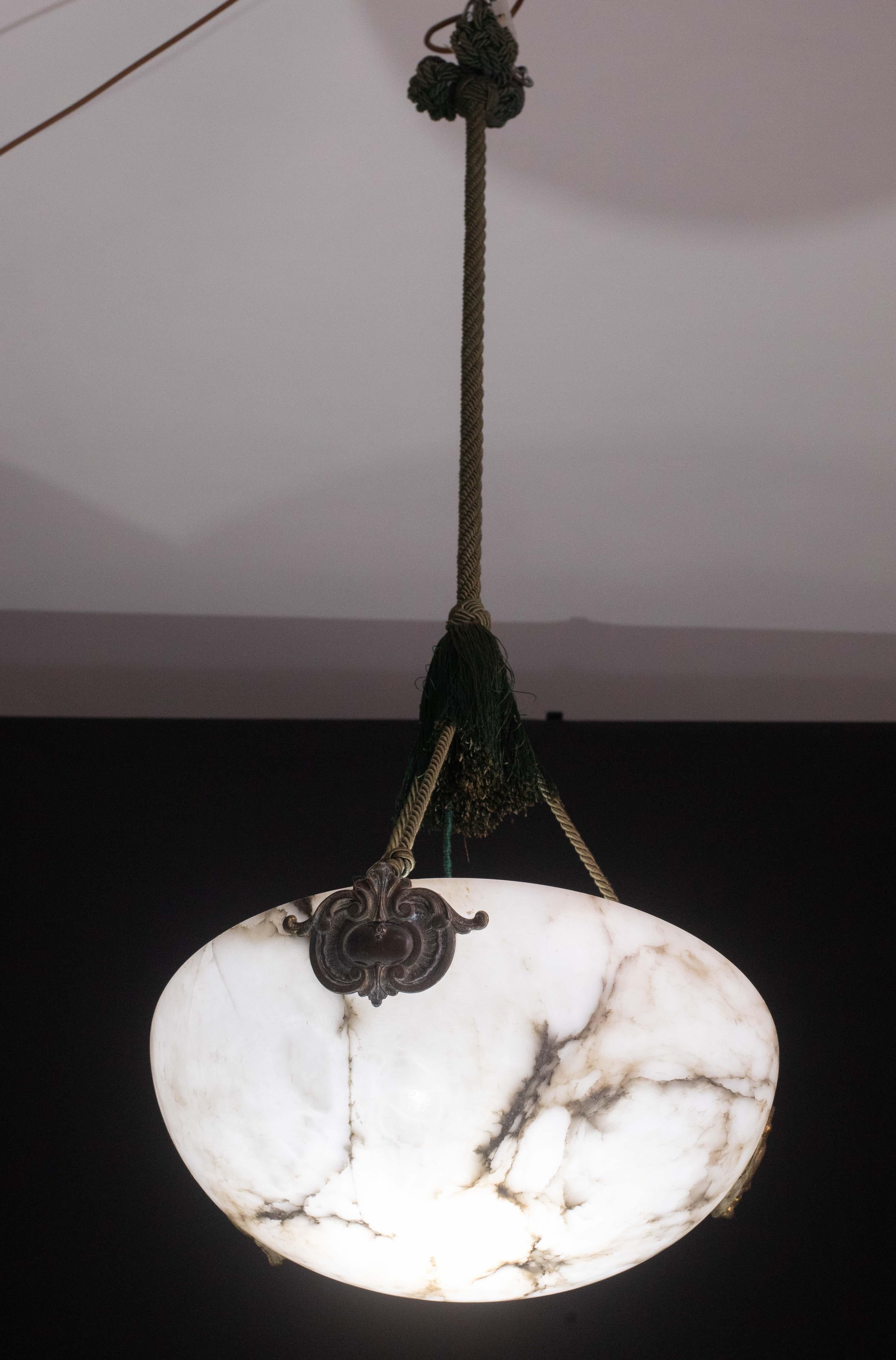 Lampada a sospensione antica in alabastro in stile Art Déco, anni '1940 circa.
Un unico pezzo di alabastro, splendidamente lavorato con sfumature e riflessi di altri colori quando è illuminato, sospeso a tre corde verdi, il suo originale, può essere