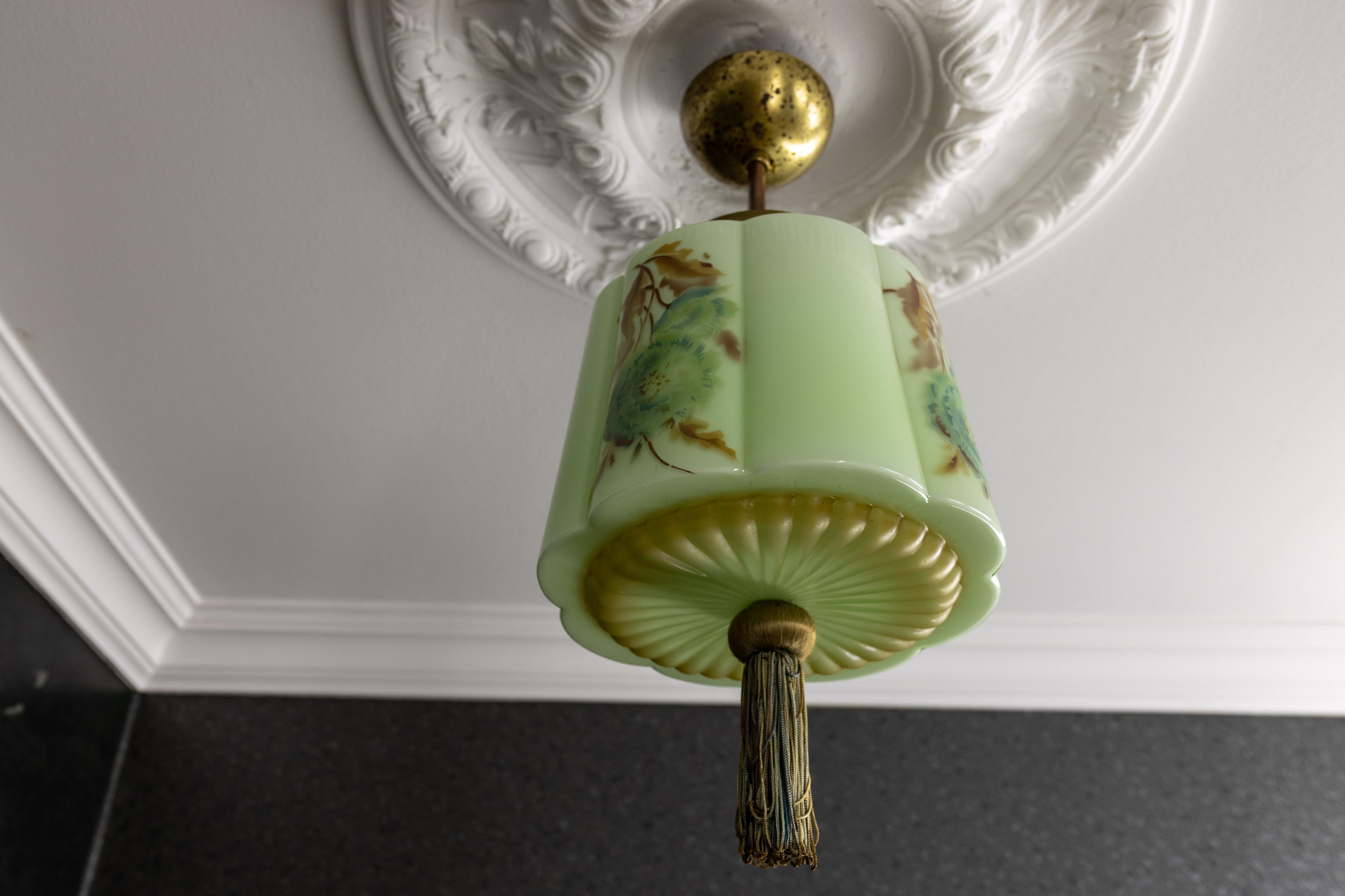 Vintage Art Deco Green Glass Pendant Light with Floral Design, 1930s, Germany. 

Add a touch of timeless elegance to your space with this exquisite Art Deco pendant light, featuring a soft green glass shade adorned with floral motifs in shades of