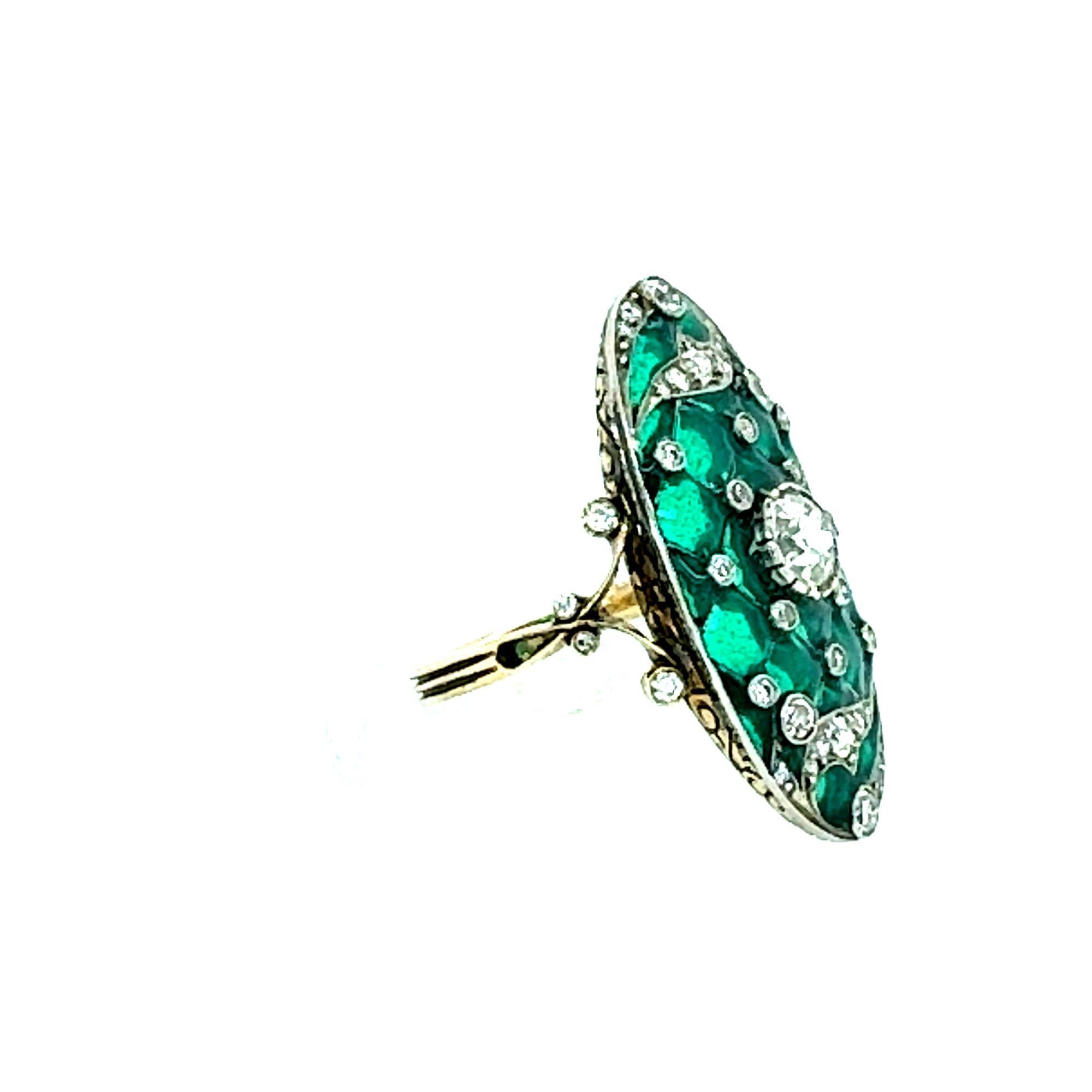 Ti presentiamo uno squisito anello d'epoca Art Déco con smalto verde e diamanti, un vero capolavoro di arte orafa. Questo splendido pezzo presenta un diamante centrale di circa 0,90 carati con colore J e purezza SI1, che irradia un'eleganza senza