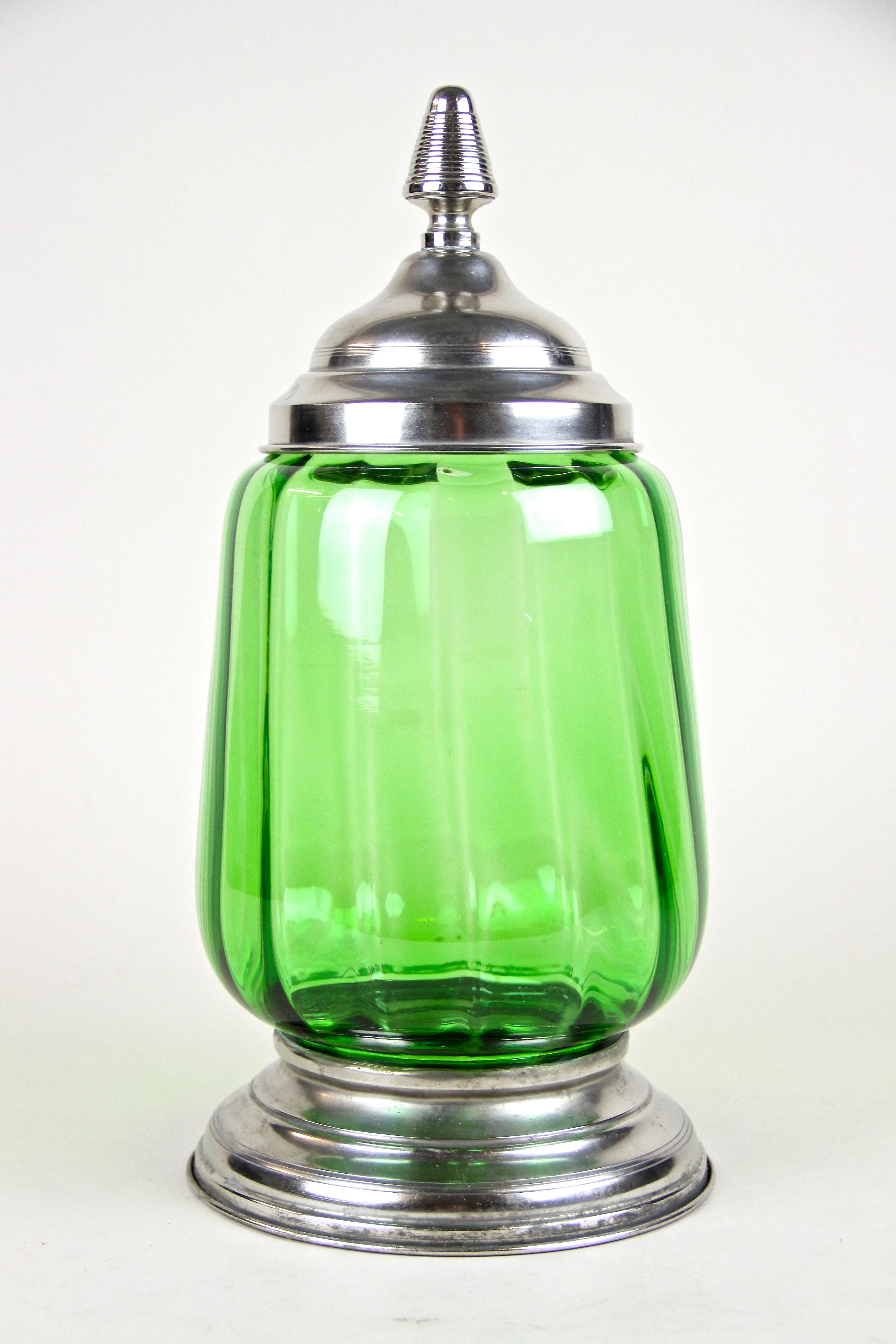 Lovely Art Deco glass jar or punch bowl from the early period around 1920 in Austria. This early 20th century green jar impresses with an artfully shaped, slightly twisted glass body embedded into a beautiful base. The removable lid with its unusual