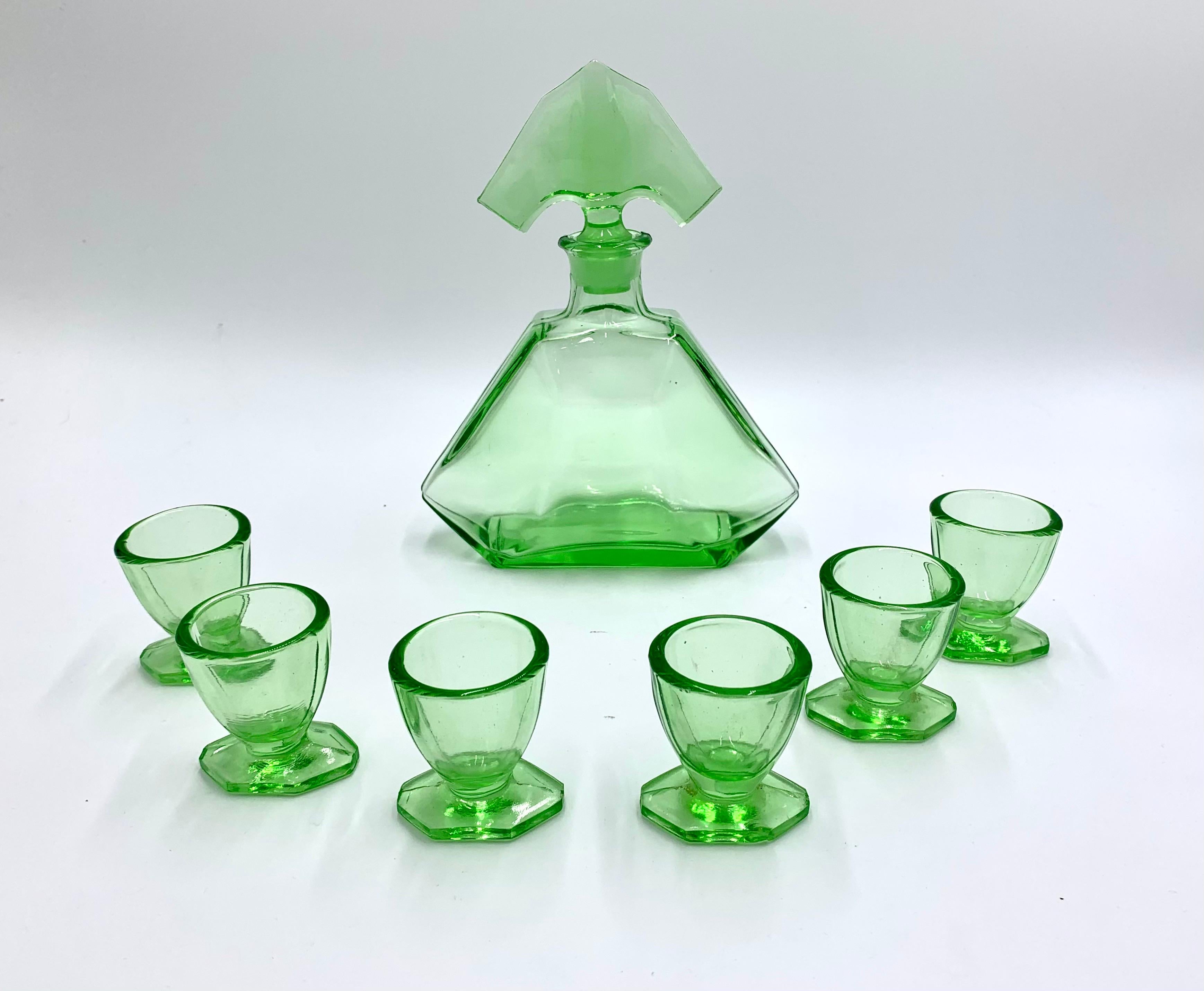 Art Deco green glass vodka or liquor set consisting of a carafe with stopper and 6 shot glasses . 
Made in Czechoslovakia in 1930s. 
Used to store absinth
Very good condition. 
Measures: Carafe height 21cm width 7cm
Glass height 5,5cm diameter 5cm.