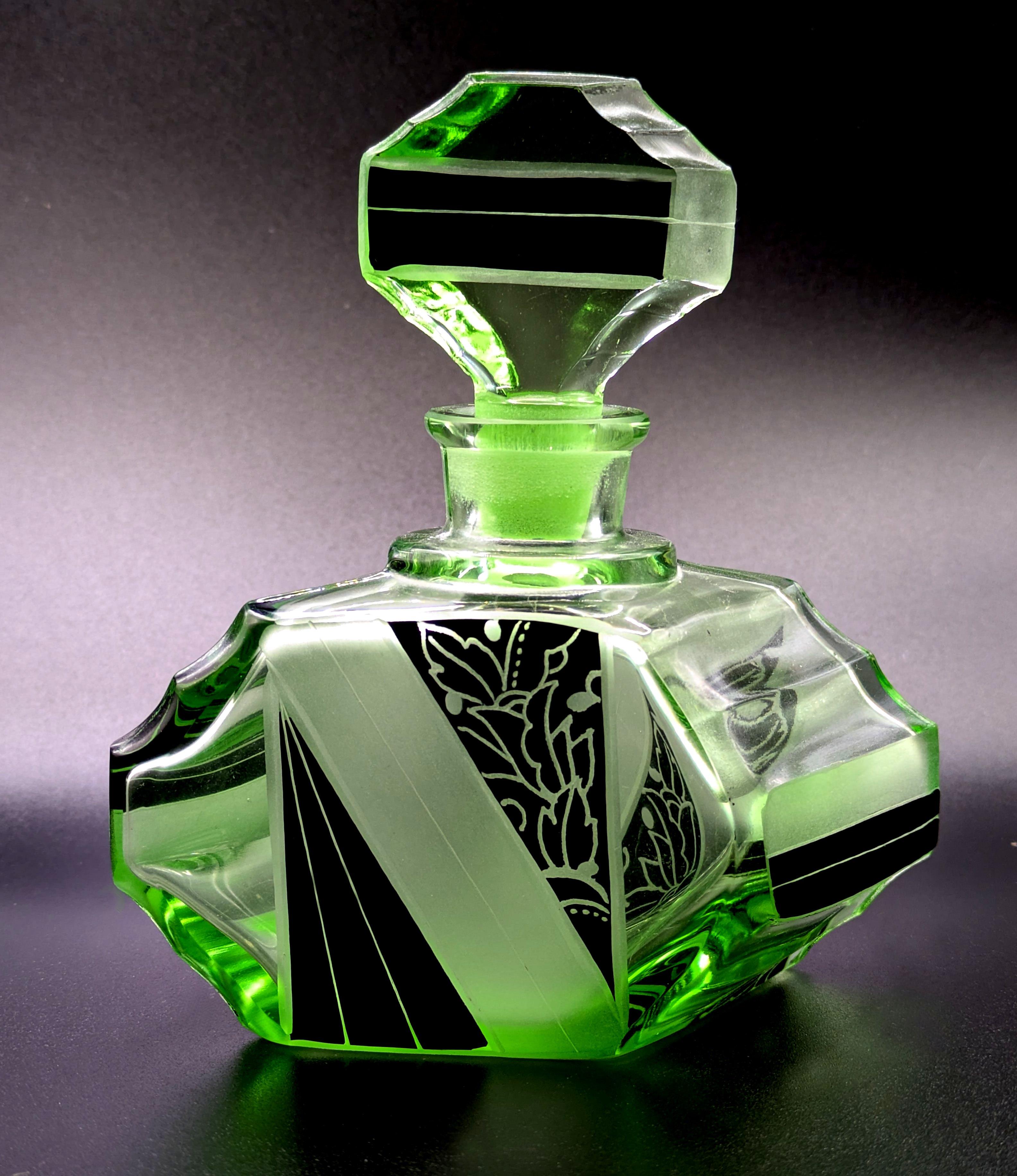 Un très beau flacon de parfum Art Deco de grande taille avec une forme et un motif très attrayants et emblématiques avec une décoration géométrique en émail noir à la fois sur le corps du flacon et sur le bouchon. Fabriquée en République tchèque
