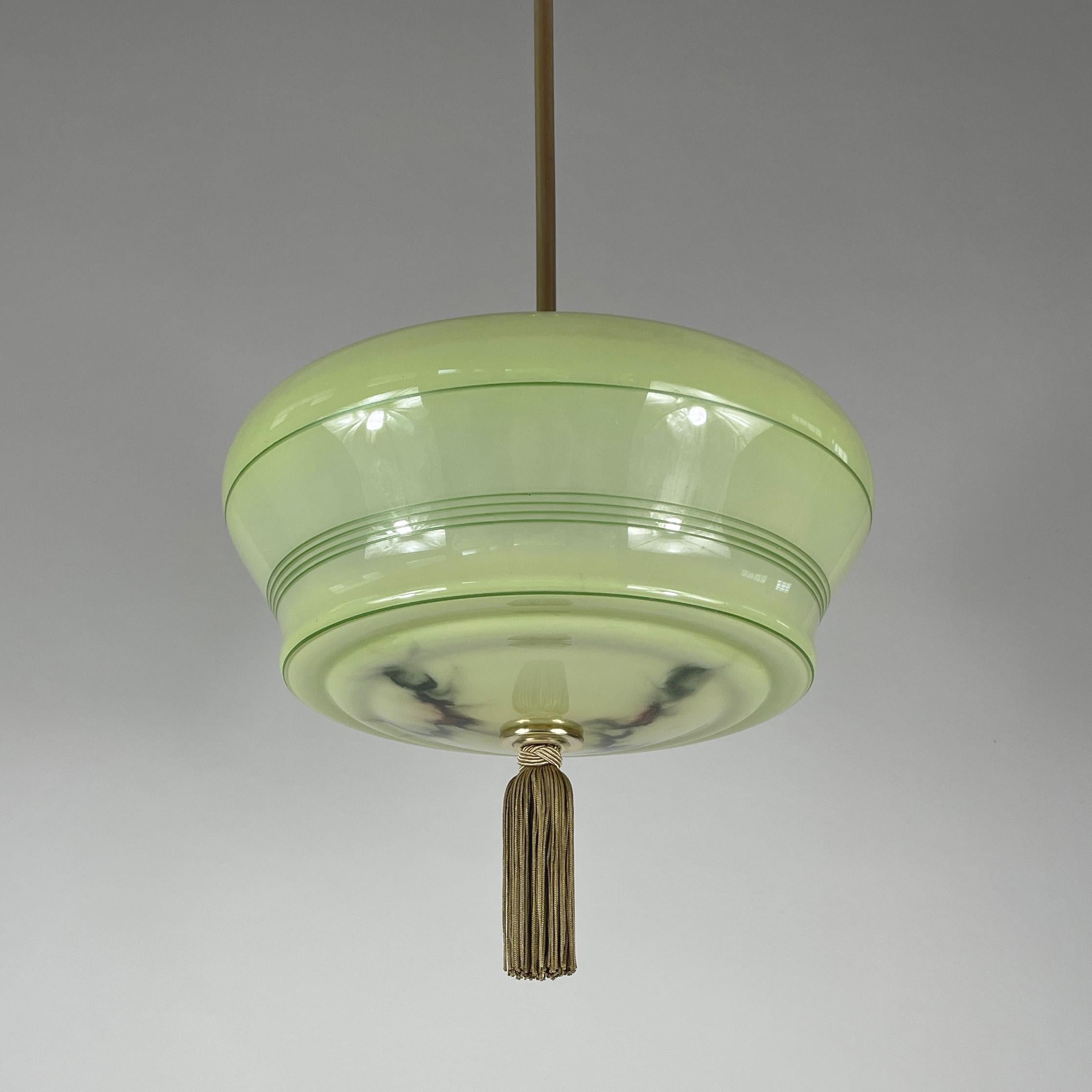 This Art Deco pendant was designed and manufactured in Germany in the 1930s during the Bauhaus period. 

The light is characterized by its streamlined, functional design typical of the movement. The light features a smooth, translucent green opaline