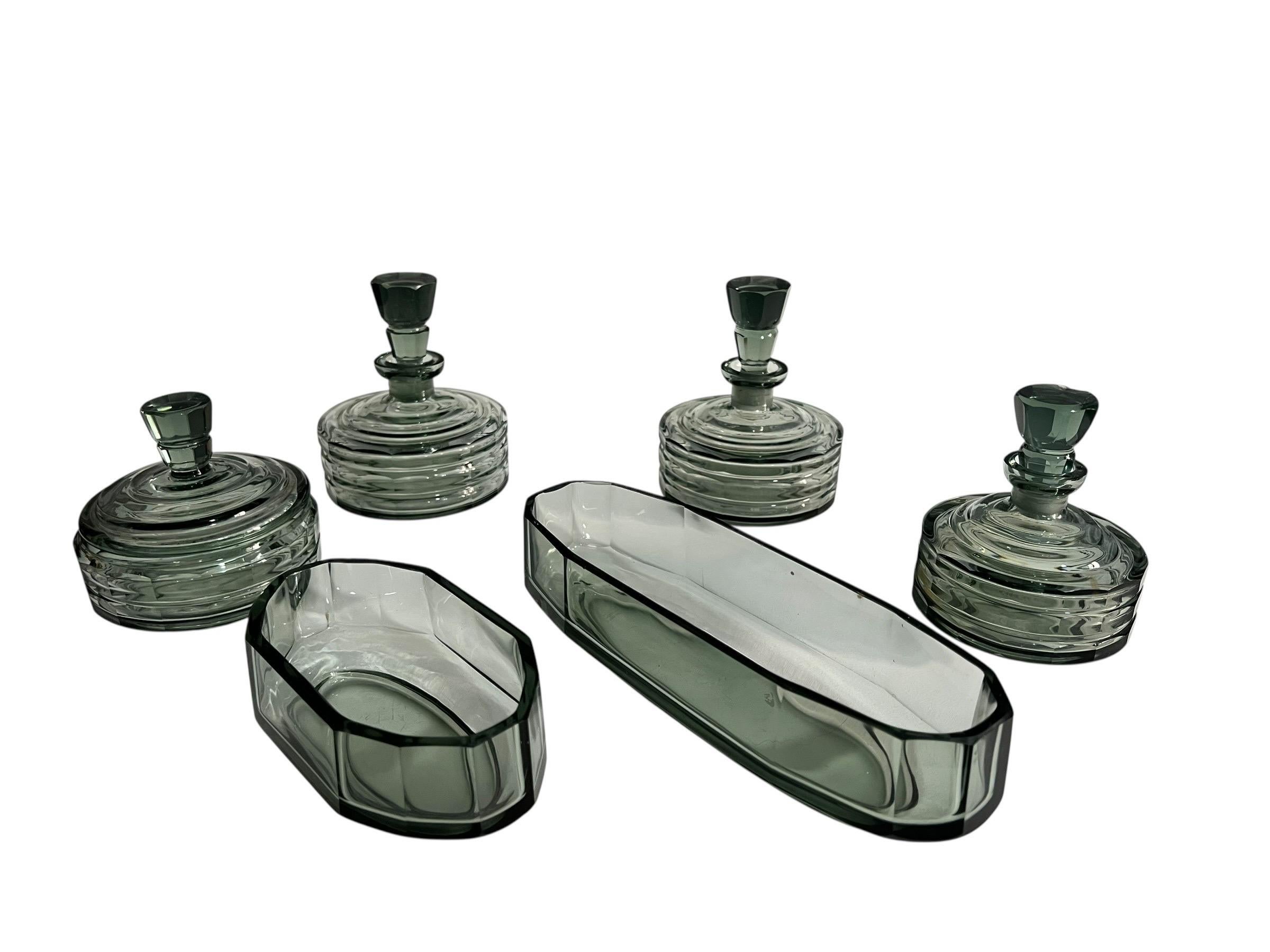 Elegant Art Deco toiletry set in molded, sea-green tinted glass, typical of Czech production from the 1930s.
It consists of six matching pieces:

- three perfume bottles with their original stoppers,

- a circular lidded box,

- an elongated oval