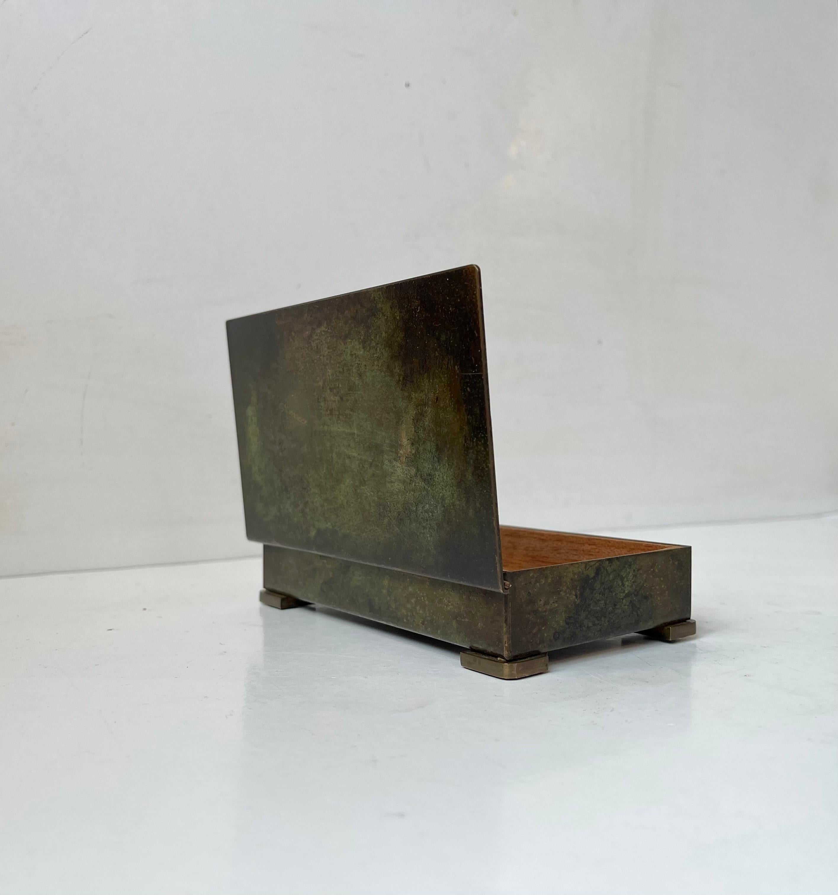 Decorative Bronze box with a dark green patina and teak interior by Metro in Denmark. Made circa 1930-40. Its suitable for cigarettes, cigars, pencils etc. Measurements: 15x8.5x3 cm.